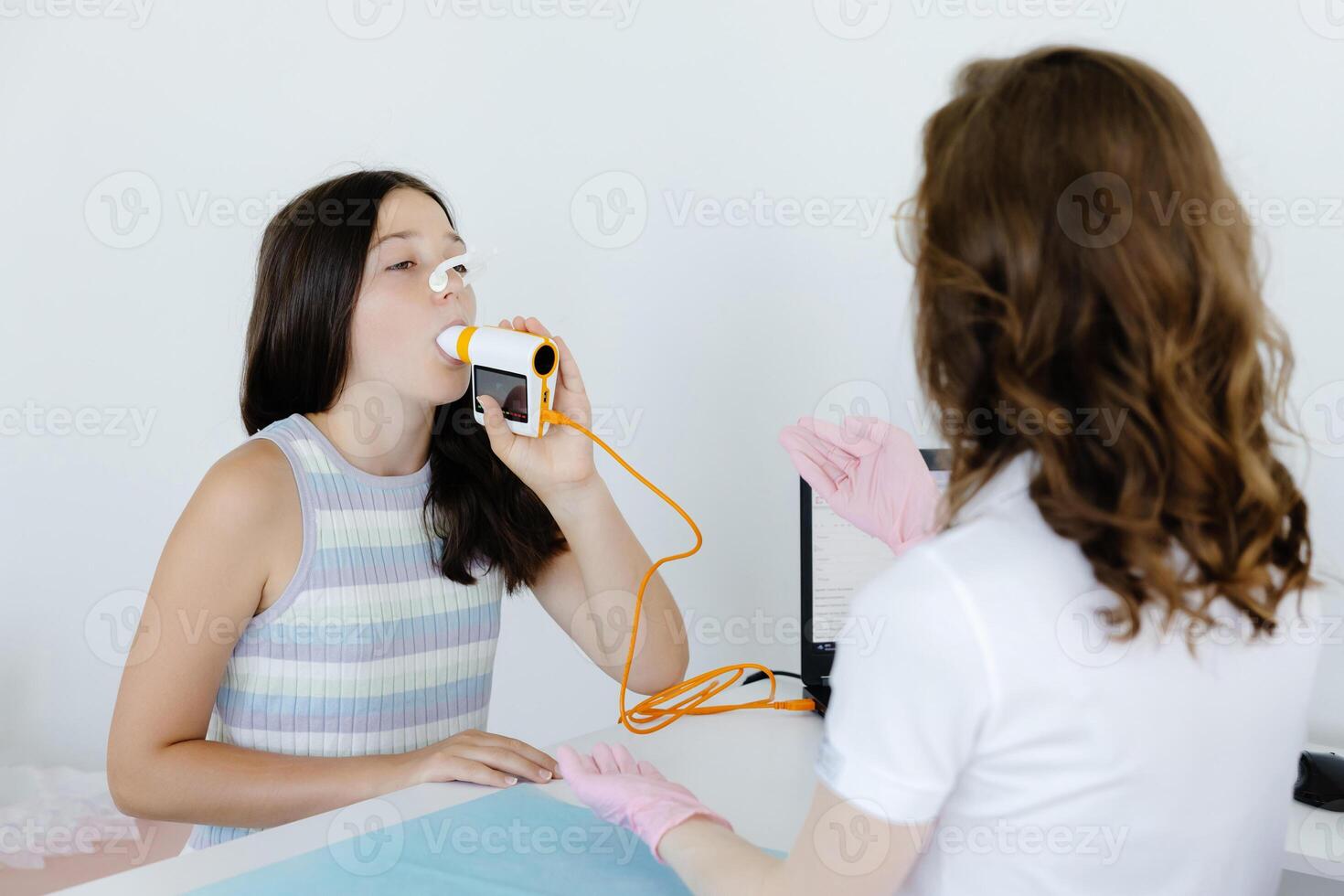 Girl testing breathing function by spirometry in doctors office. Diagnosis of respiratory function in pulmonary disease photo
