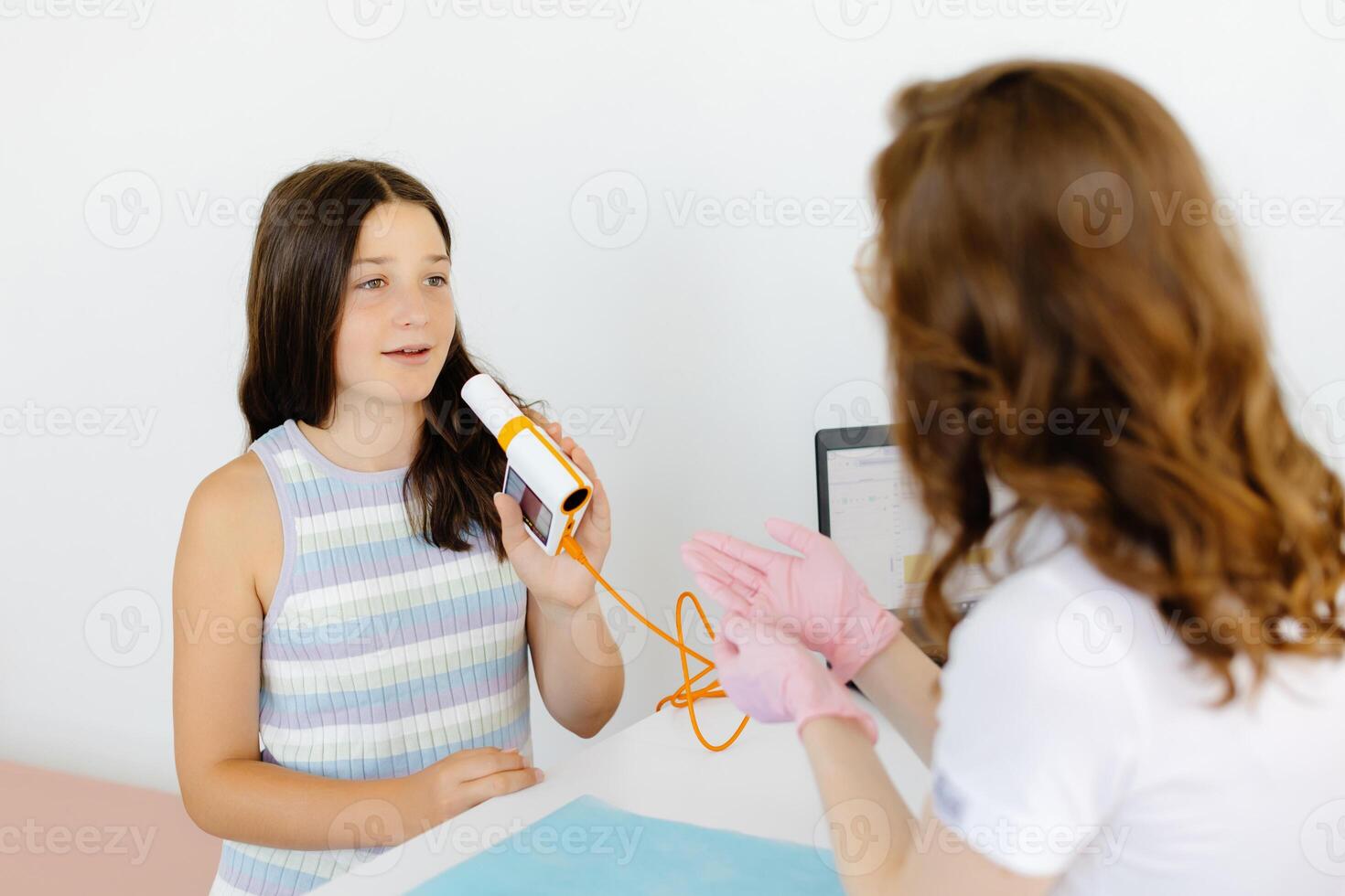 Girl testing breathing function by spirometry in doctors office. Diagnosis of respiratory function in pulmonary disease photo