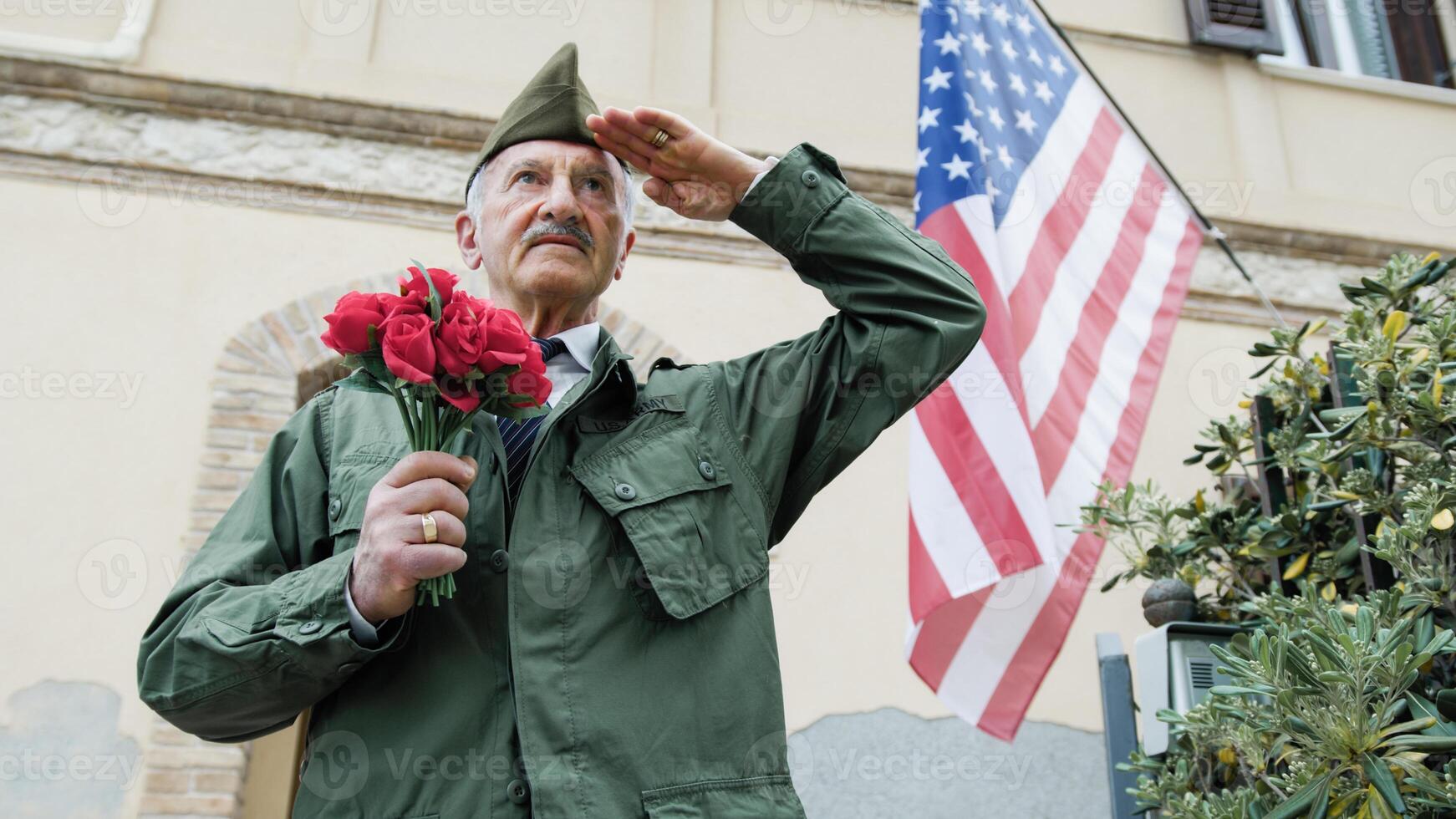 Elderly Veteran Man Salutes In Front Of The American Flag photo