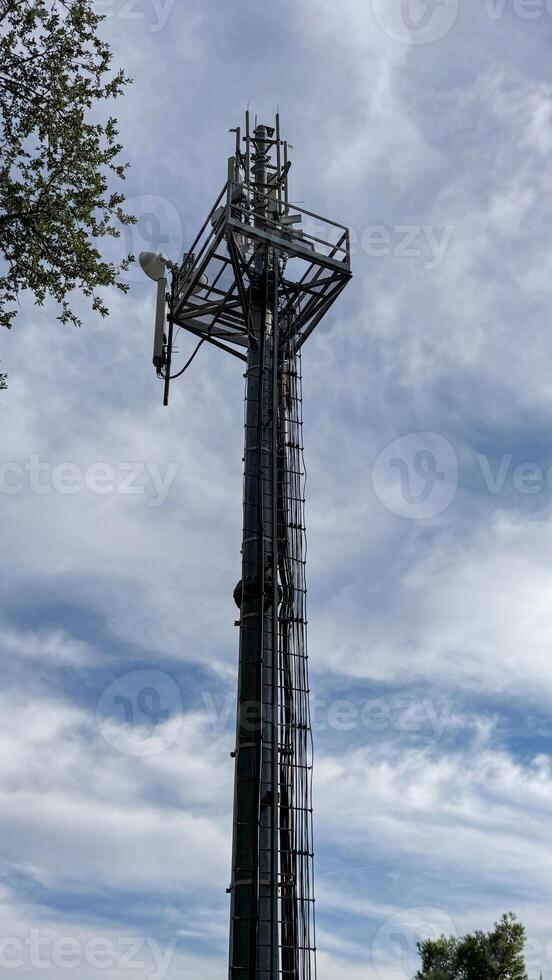 A tall metal communication tower rises against a partly cloudy sky. industrial structure photo