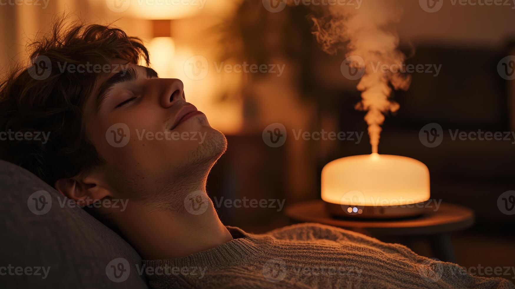 Young man unwinds on the couch, enjoying the calming effects of an aromatherapy diffuser nearby. photo