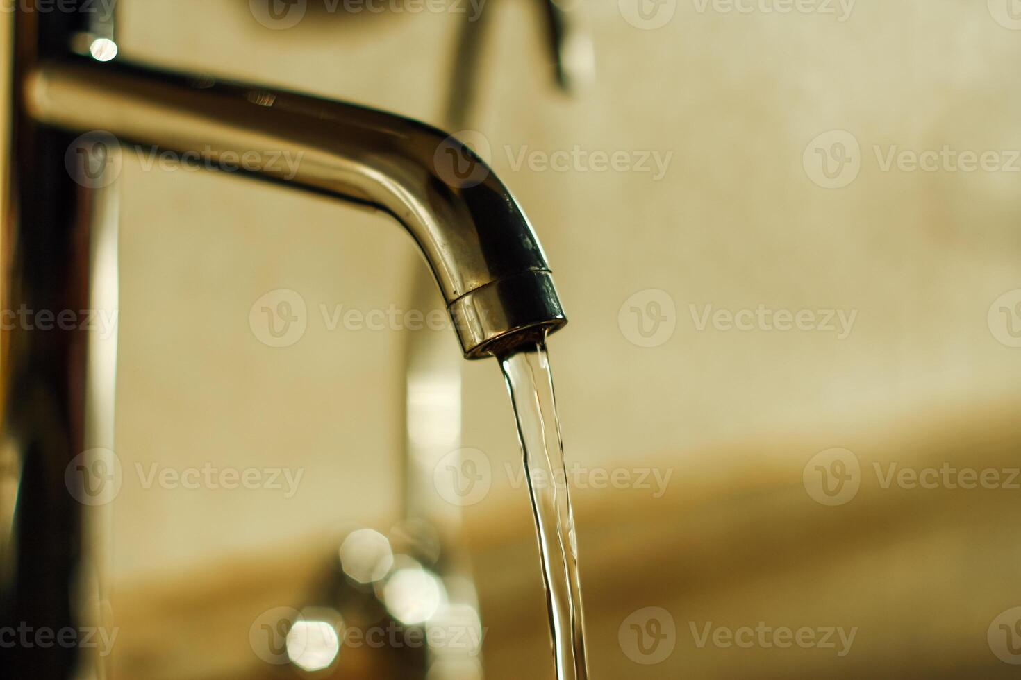 water is flowing from a chrome faucet. Plumbing in the bathroom or in the kitchen. The use of water resources. Selective focus photo