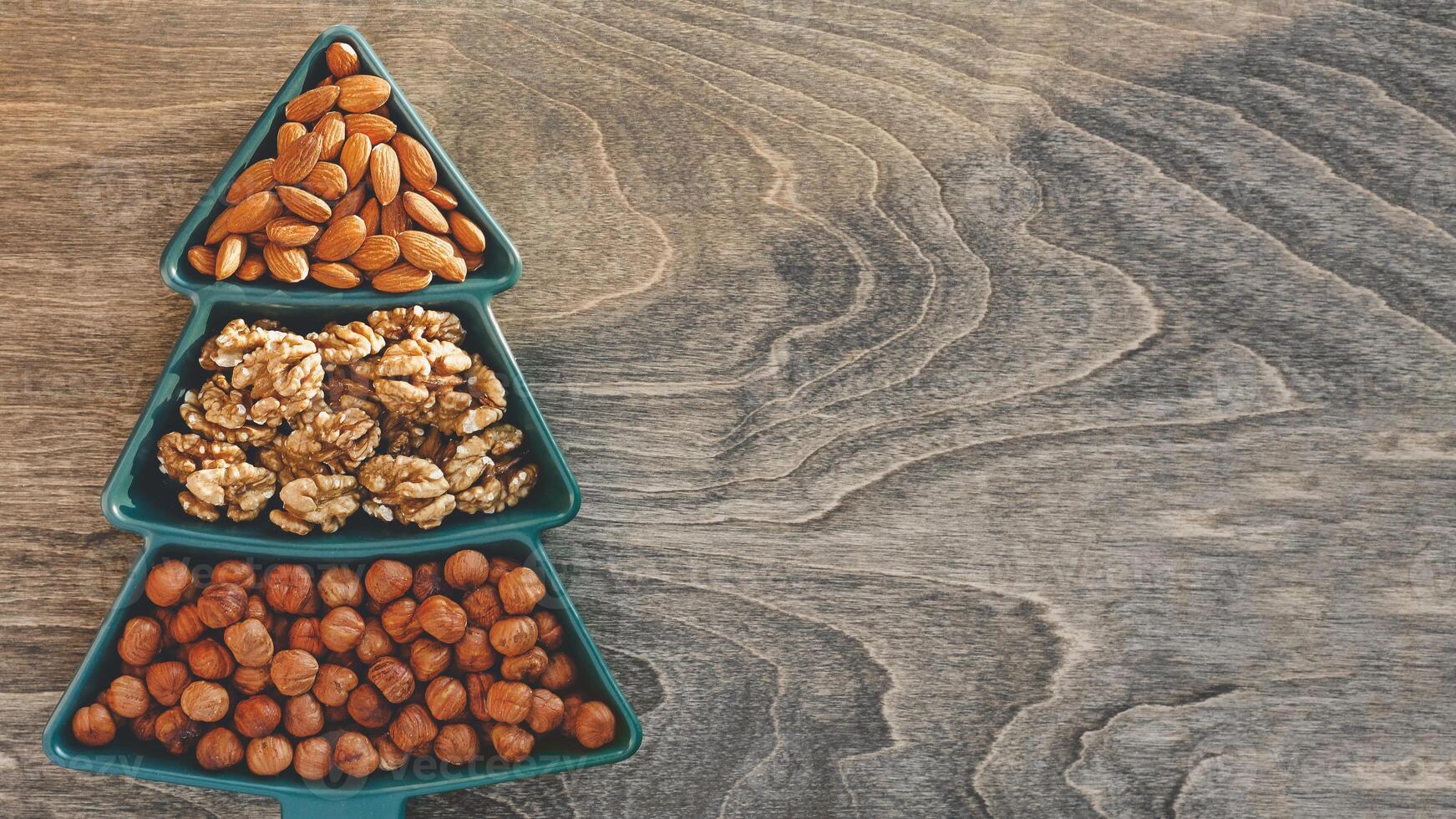 different types of nuts, Various snacks for the New Year table in a plate in the shape of a Christmas tree. photo