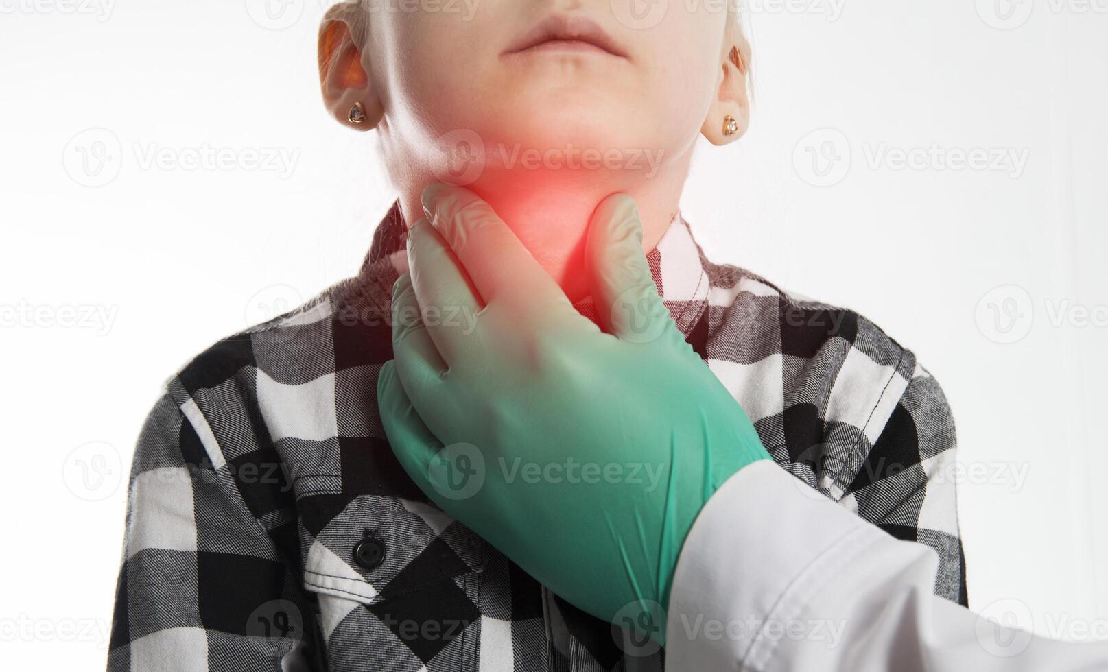 The hand of an endocrinologist palpates the thyroid gland of a seven-year-old girl. Concept of dysfunction of thyroid hormones. Lack of iodine, hypothyroidism. Copy space for text photo