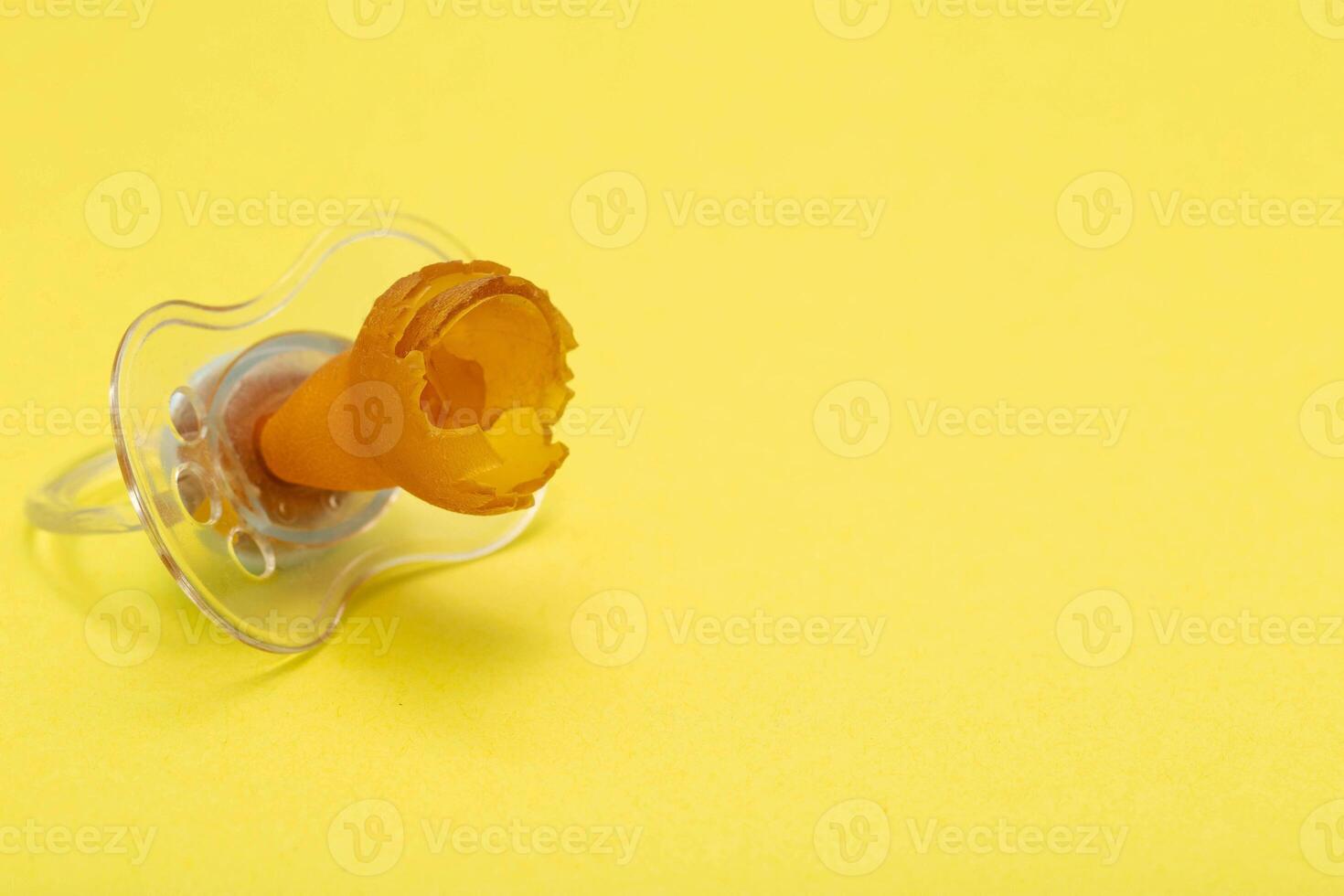 A chewed baby pacifier on a yellow background. Concept of teething in children, close-up. Copy space for text photo