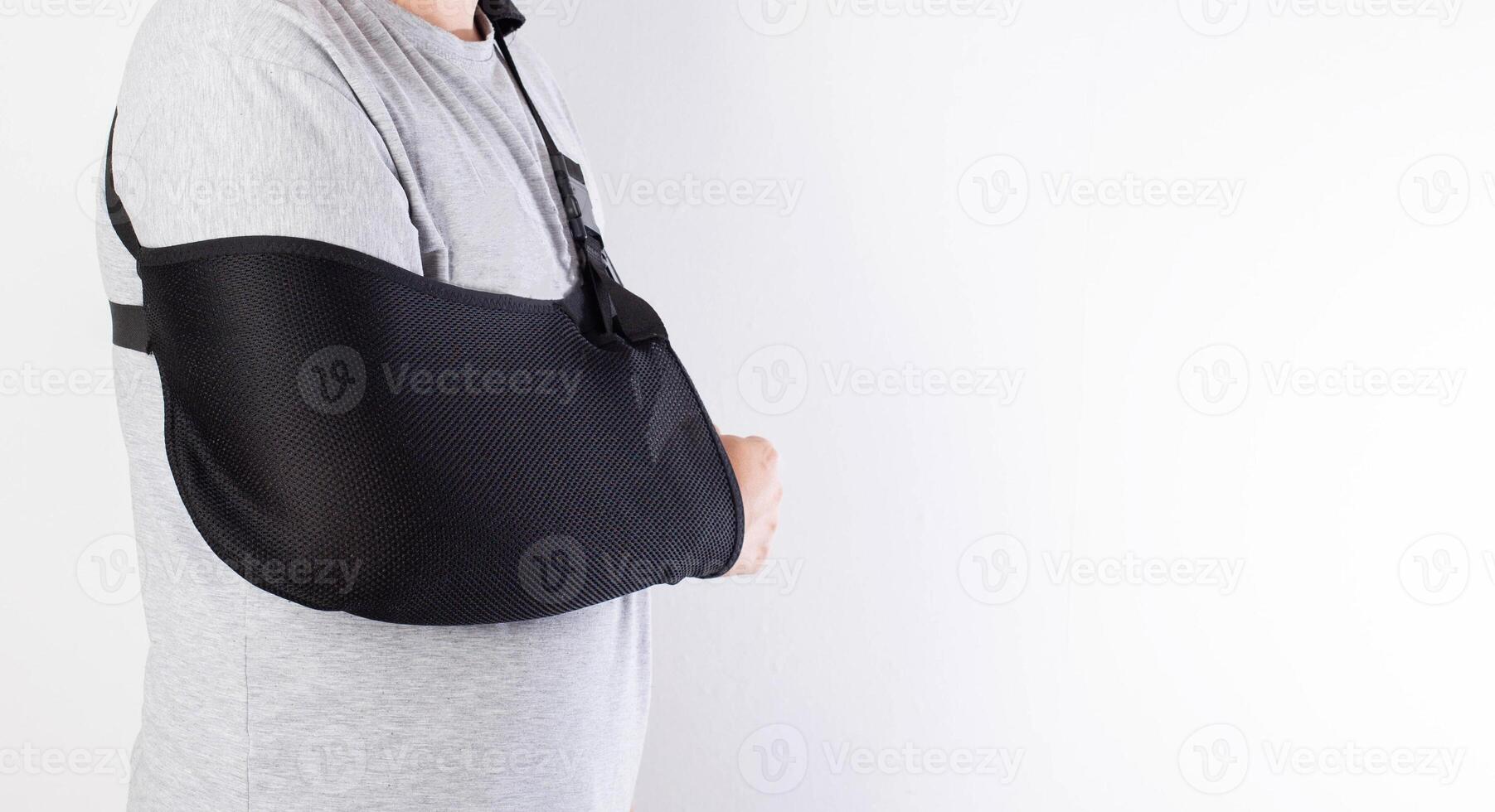 A man on a white background in a bandage to support his arm. Immobilization of the hand and forearm after injury. Rehabilitation after a broken bone. Orthopedics, copy space for text photo