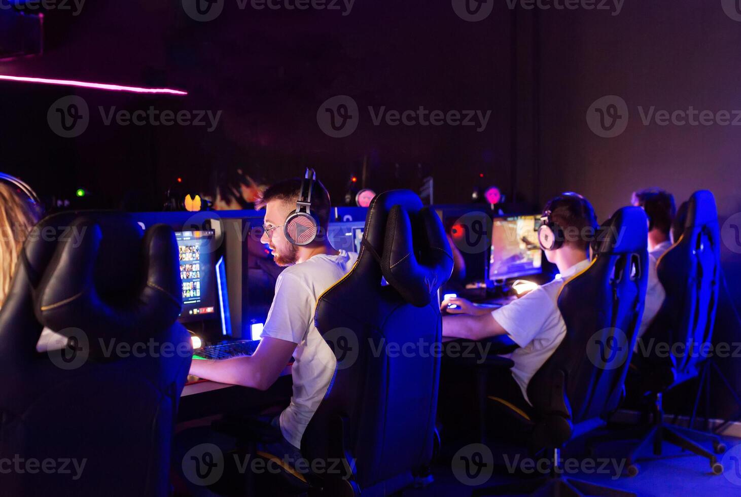 Gamers team playing game on PC at computer club, cyber sport tournament. E-sport championship. Five guys in headset, left-handed player. Multiplayer online battle, first-person shooter photo