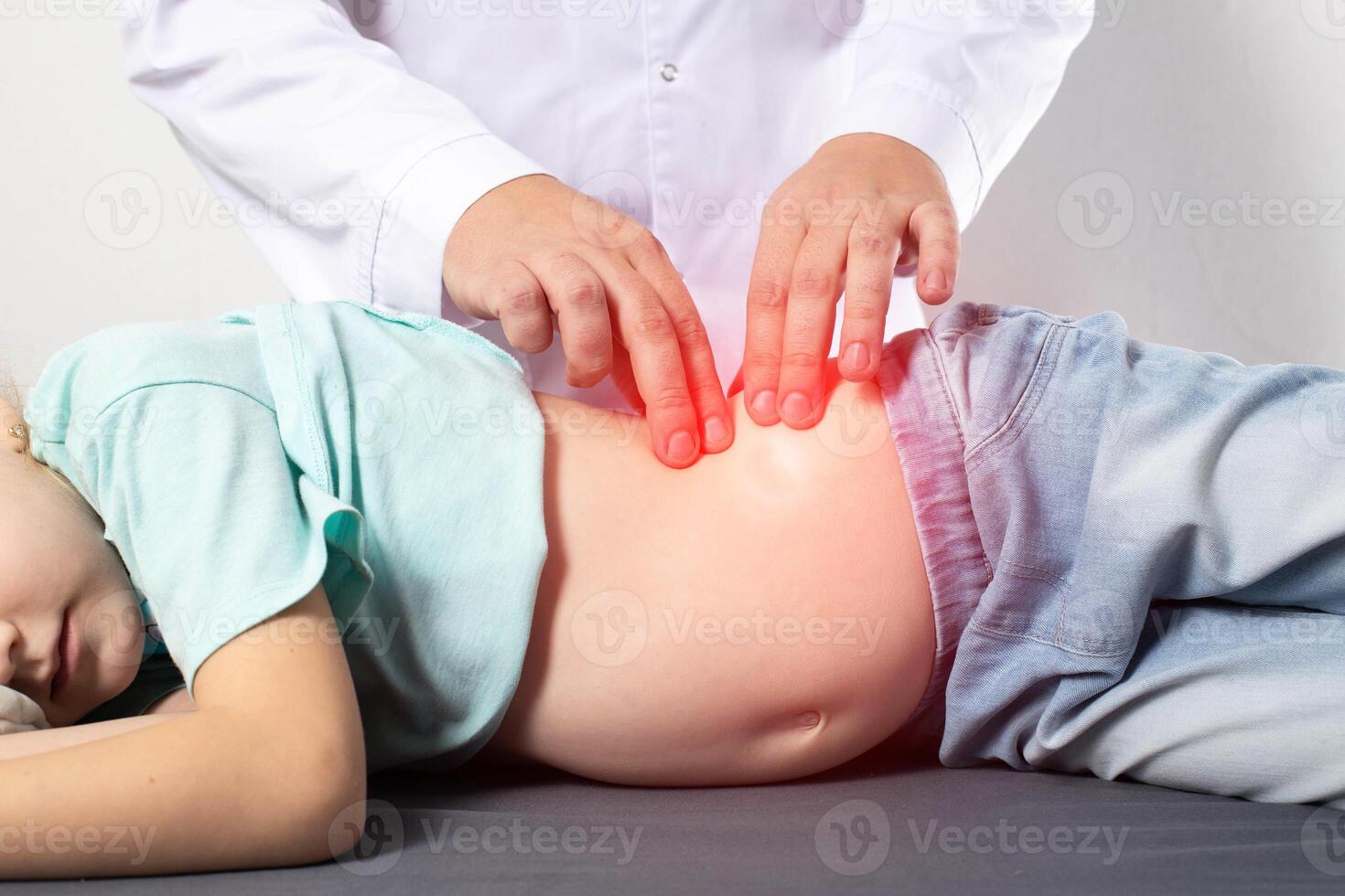 A doctor surgeon examines and diagnoses the abdomen of a seven-year-old little girl who has abdominal pain. Concept of appendicitis in children, nausea and discomfort. photo