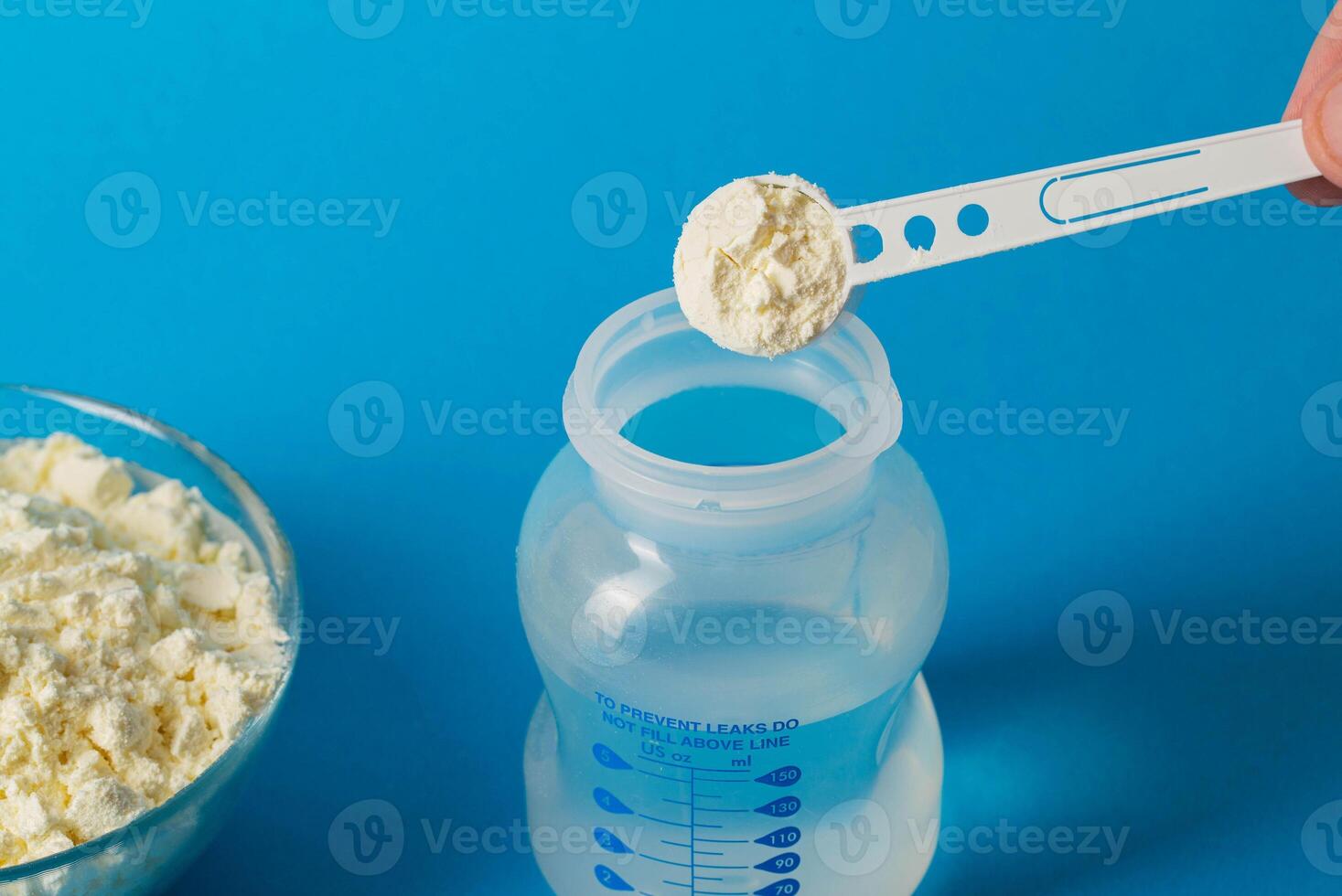 Preparation of baby milk food for feeding babies. Powdered milk mixture with vitamins and minerals on a blue background. Copy space for text, immune photo