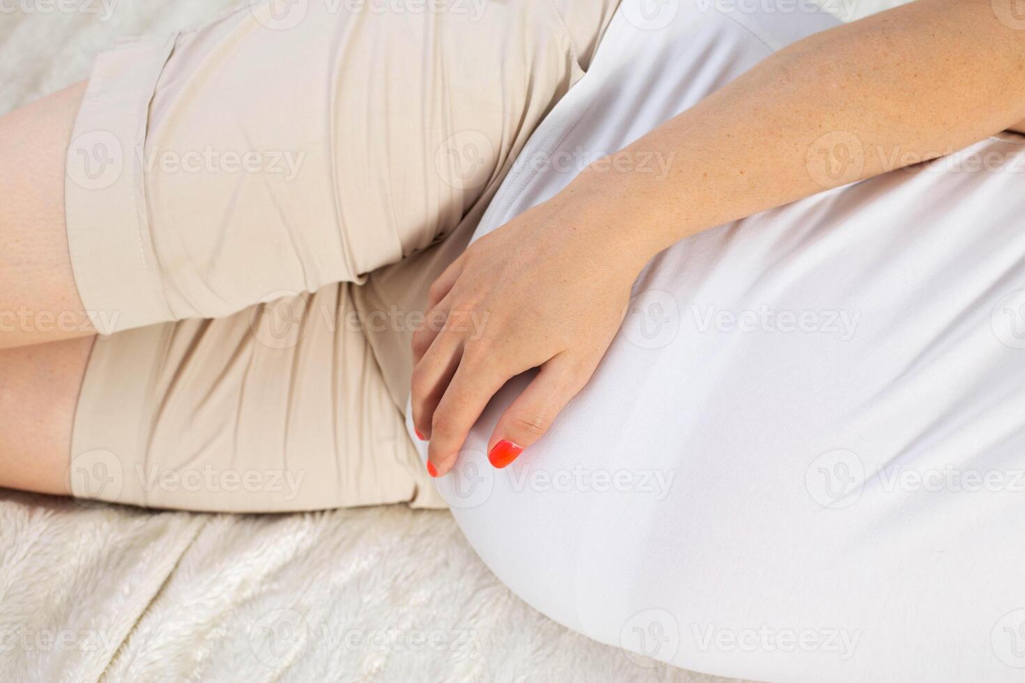 a pregnant girl lies on the bed and holds her stomach. Concept of cystitis and inflammation of the urinary tract and bladder in pregnant women. photo