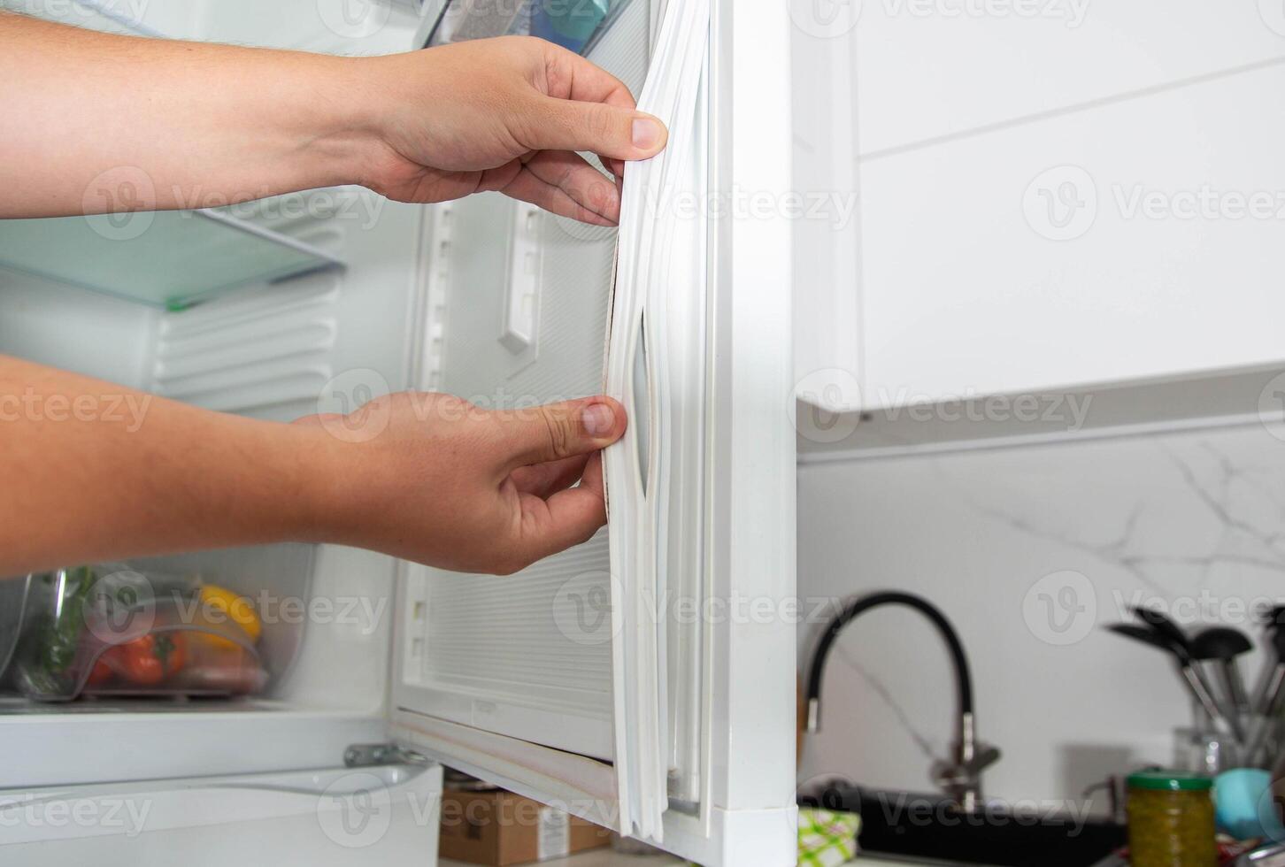Torn and damaged sealing gum on the refrigerator door. Replacing the old sealing rubber with a new one photo