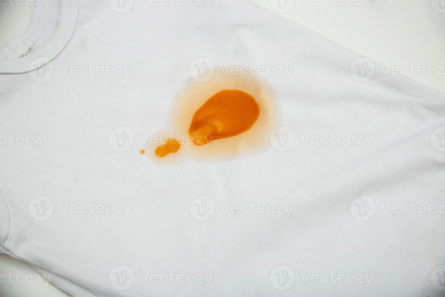 Orange stains on children's clothes from fruit puree. The concept of cleaning stains on clothes with an oxygen stain remover, close-up photo