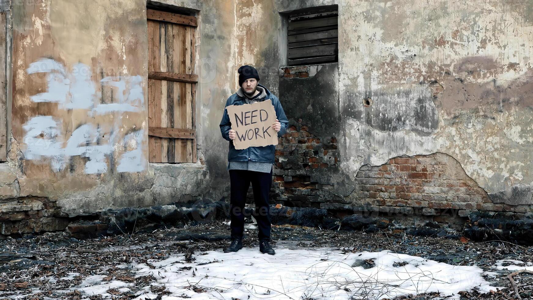 Homeless holds piece of cardboard with inscription Need Work. Refugee is looking for job. Male tramp in dirty clothes. Below poverty line. Bearded fugitive beggar. Immigrant. Drunkenness photo