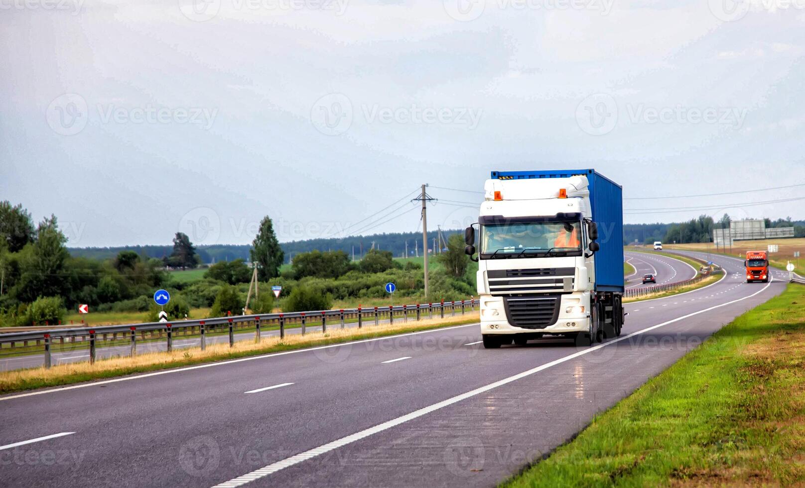 A container truck with a semi-trailer transports cargo from a port to another country along the highway in the summer, merchandise photo