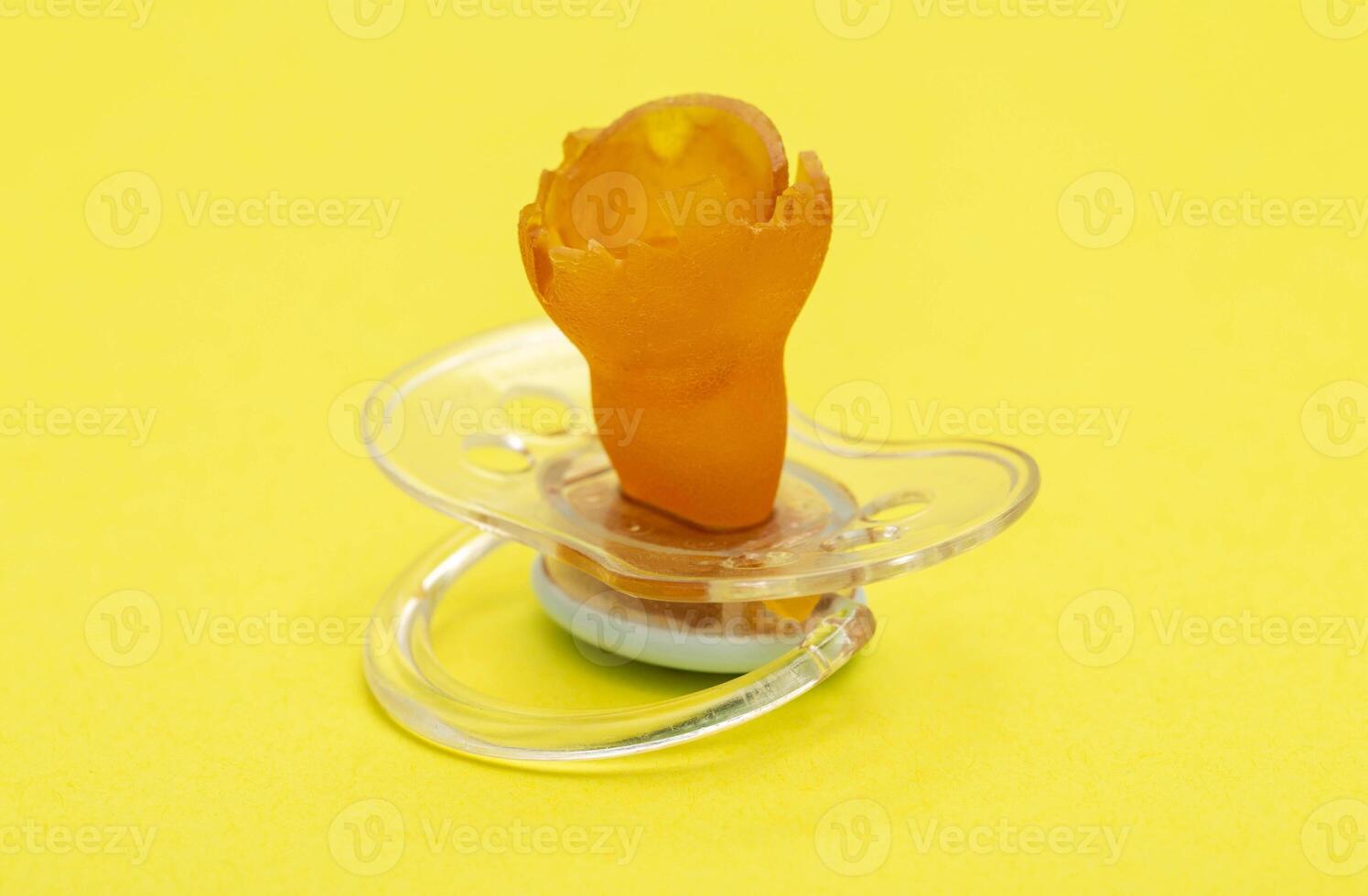 A chewed baby pacifier on a yellow background. Concept of teething in children, close-up. photo