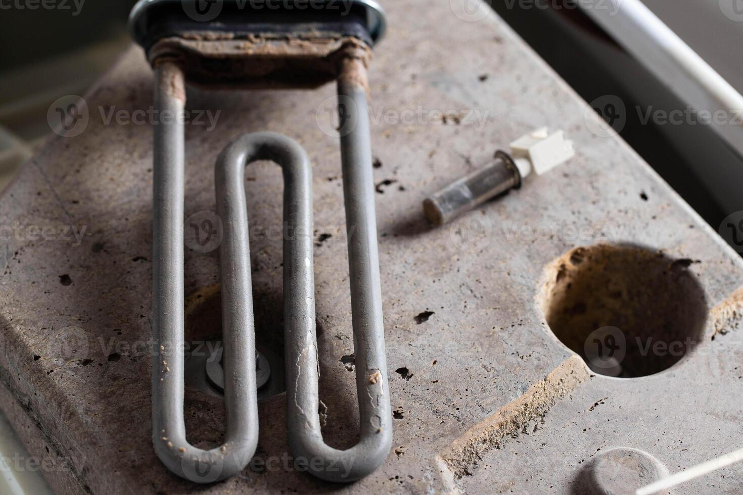 The electric heating element and temperature sensor, thermostat are on the disassembled washing machine. The concept of replacing and repairing spare parts in a washing machine. photo