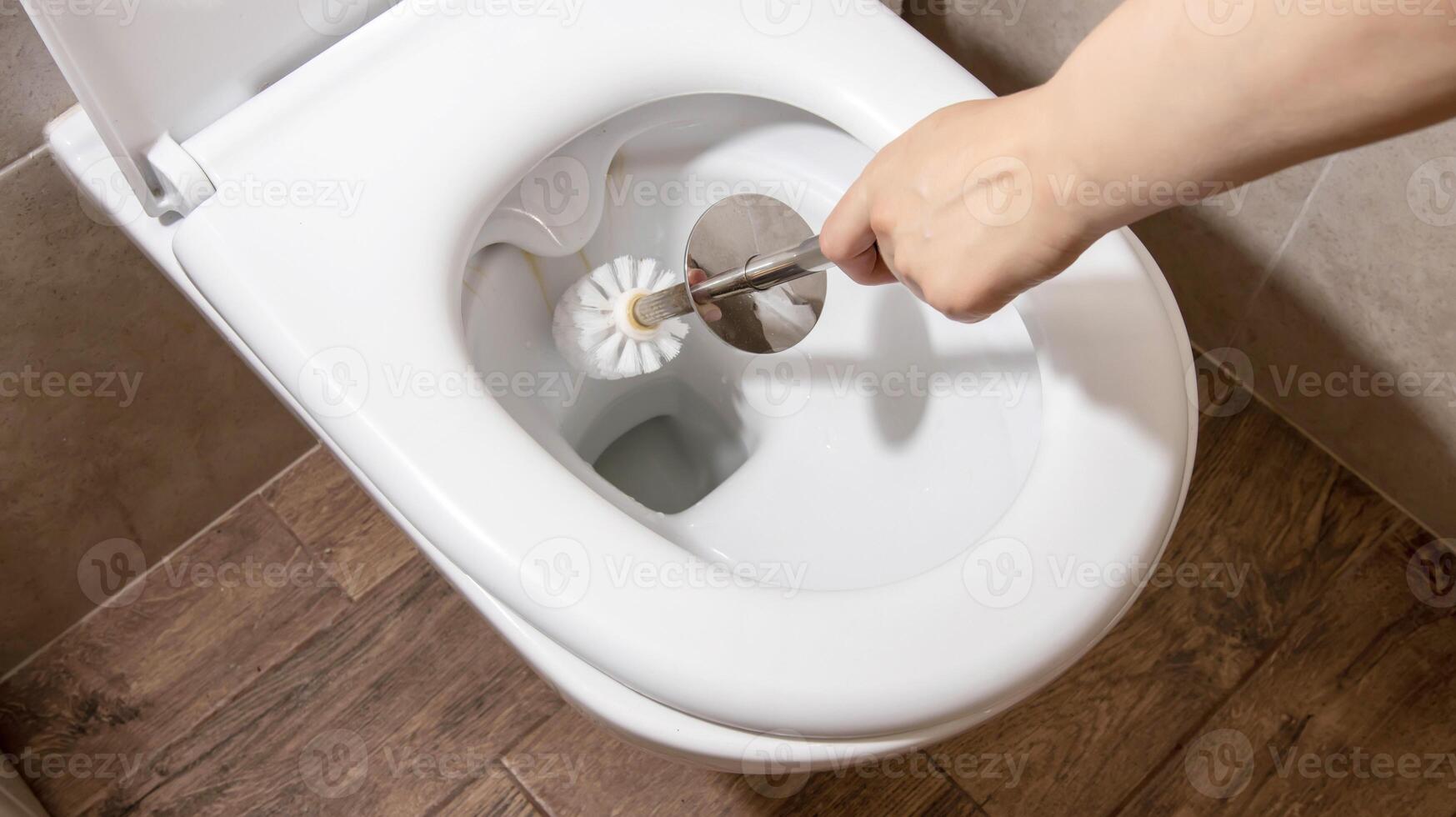 A man cleans and washes the toilet bowl with a toilet maintenance brush. Hygiene and sanitation in the toilet, housework photo