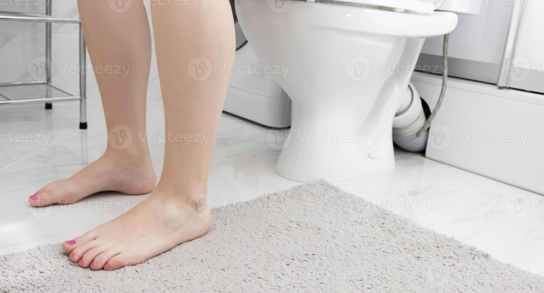 Legs of a girl who sits on the toilet. The concept of the problem of urination disorders or symptoms of the lower urinary tract in girls, dribbling. Diseases cystitis in urology. Copy space for text photo