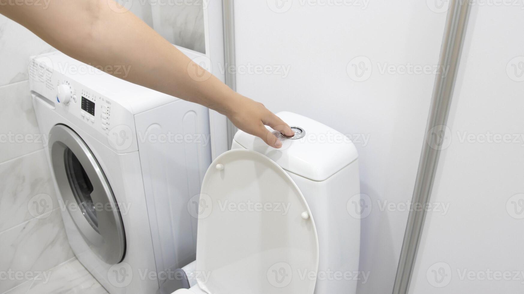 The girl presses the button to drain the water from the toilet tank. The concept of water leakage, repair of the mechanism for draining water from the toilet, defect photo