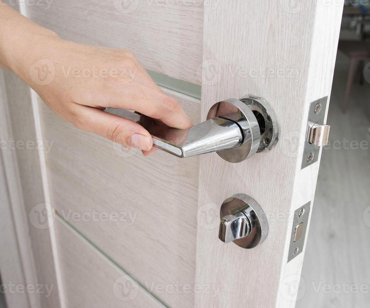 A man's hand opens an interior door with a broken doorknob. Poor quality door hardware, breakage, damage. photo