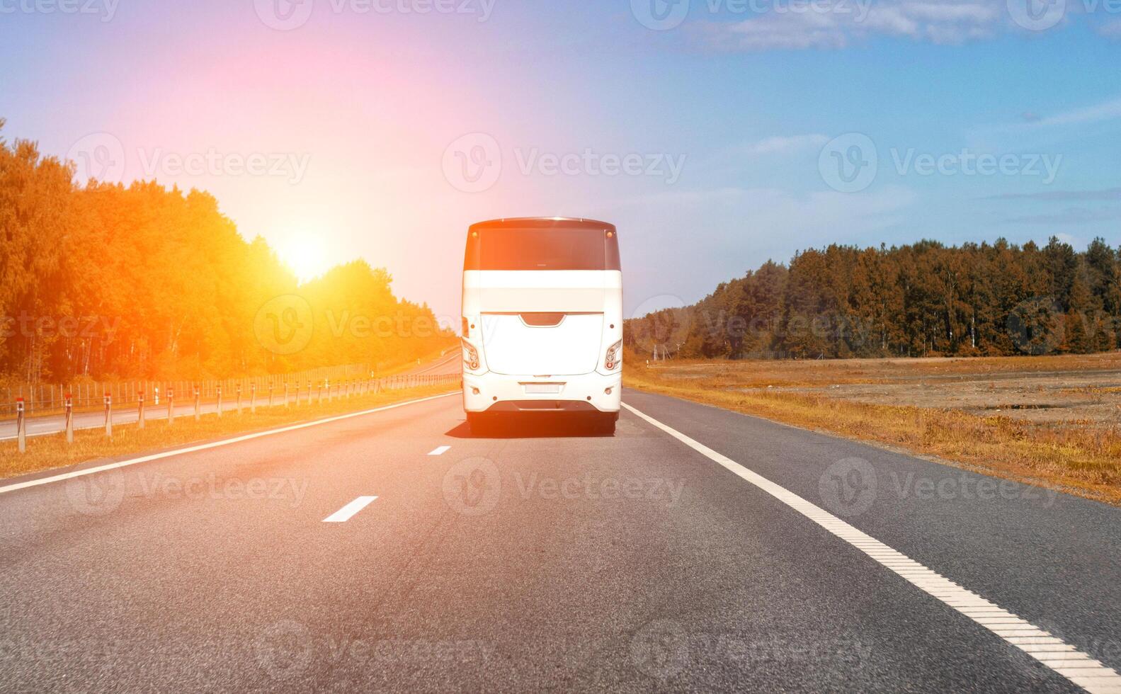 A modern comfortable passenger bus rides along the highway against the backdrop of the sun in summer. The concept of European tours by bus. Copy space for text photo