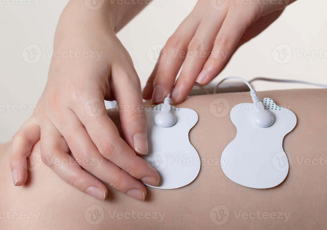 Electrodes of modern acupuncture and anti-cellulite massagers on the legs of a girl in problem areas. Home physiotherapy, close-up photo