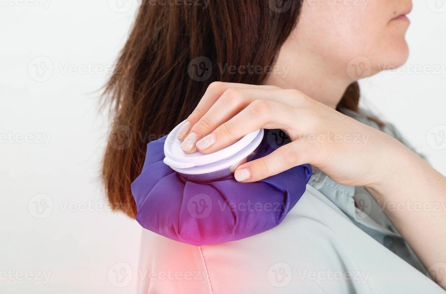 A girl holds a medical ice bag on her shoulder joint for torn and sprained ligaments, arthrosis and arthritis. Close-up photo