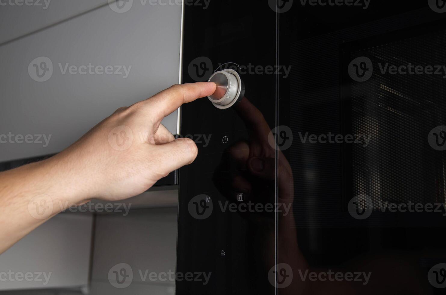 A man's hand presses a button-regulator on a modern microwave oven child protection, close-up. Copy space for text photo