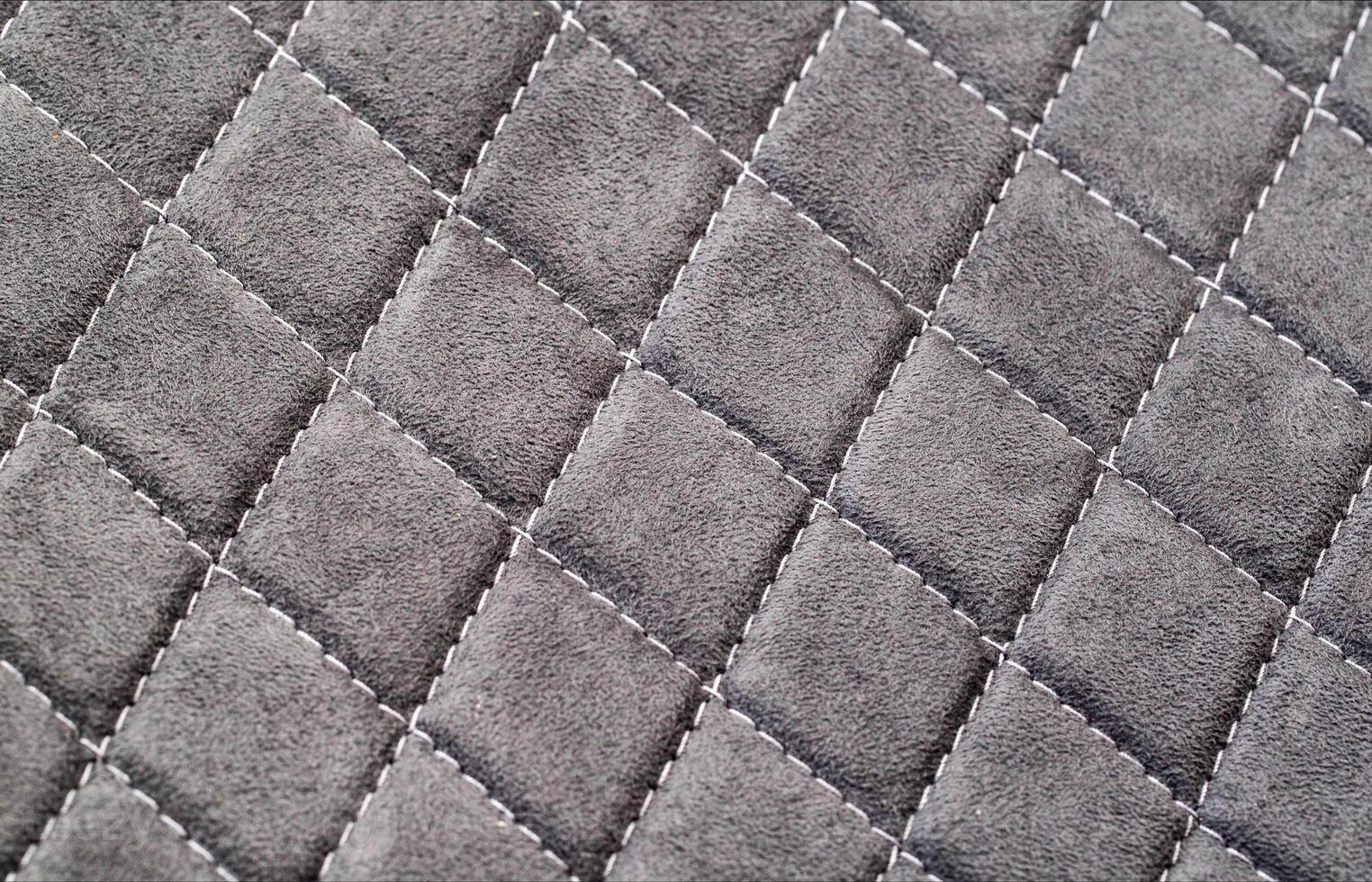 Factory fabric with stitched stitching in the form of gray diamonds. Background, close-up photo