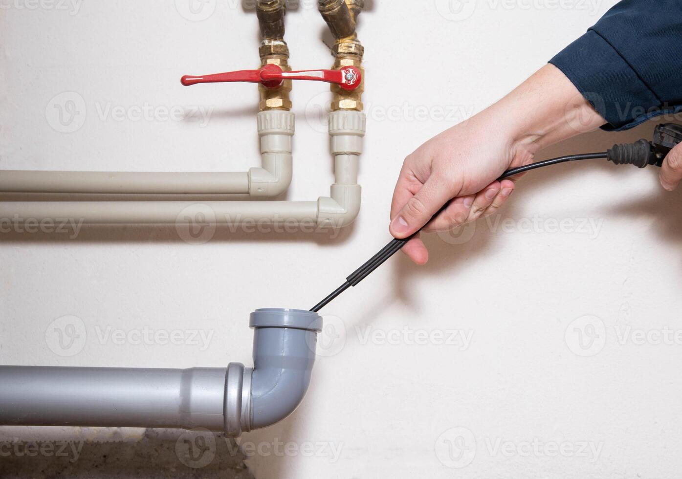 Cleaning the sewer drain pipe with a manual plumbing cable. Sewer blockage, close-up photo