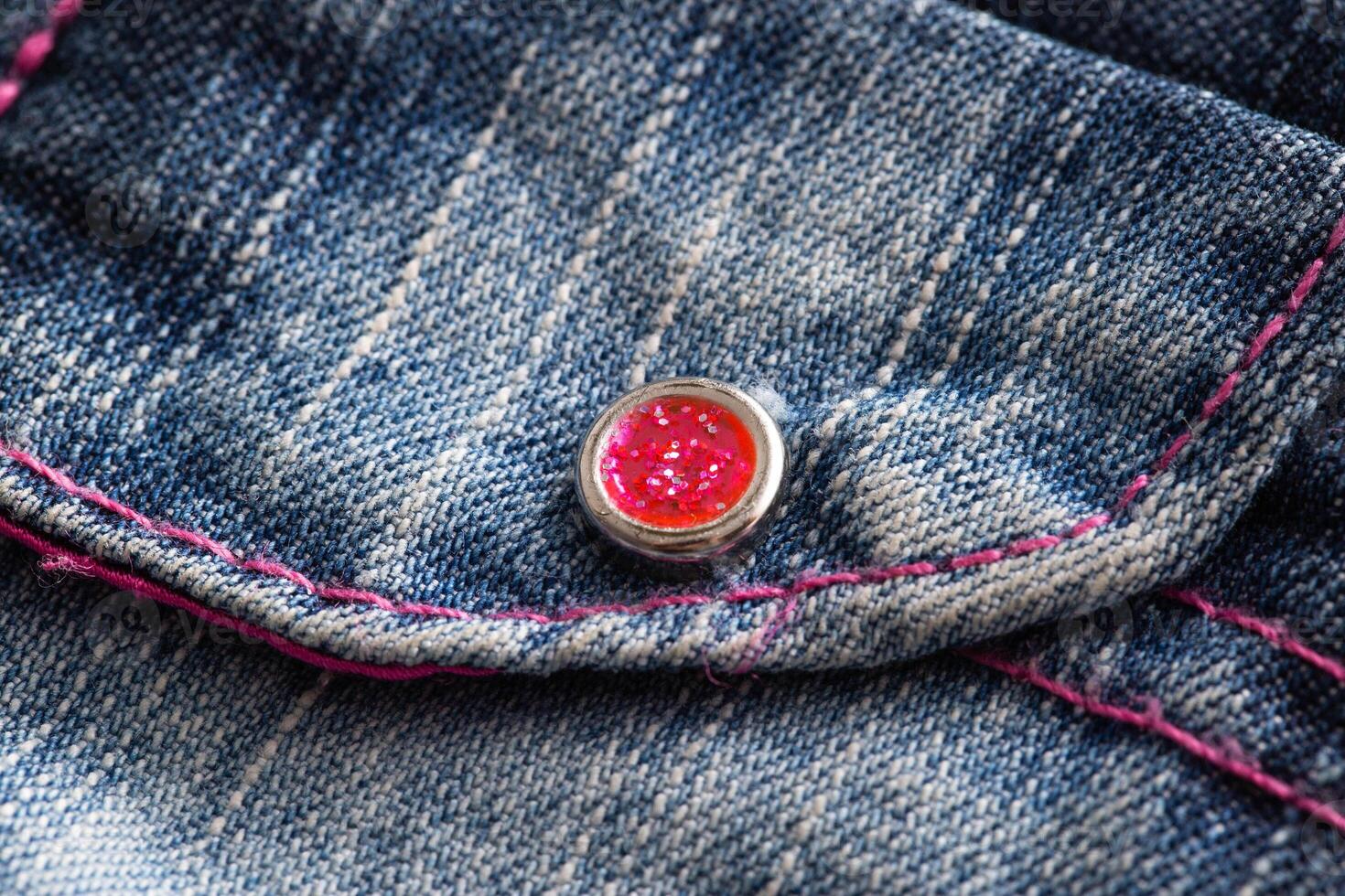 Blue denim, background. Stylish jeans, macro, design. Red button photo