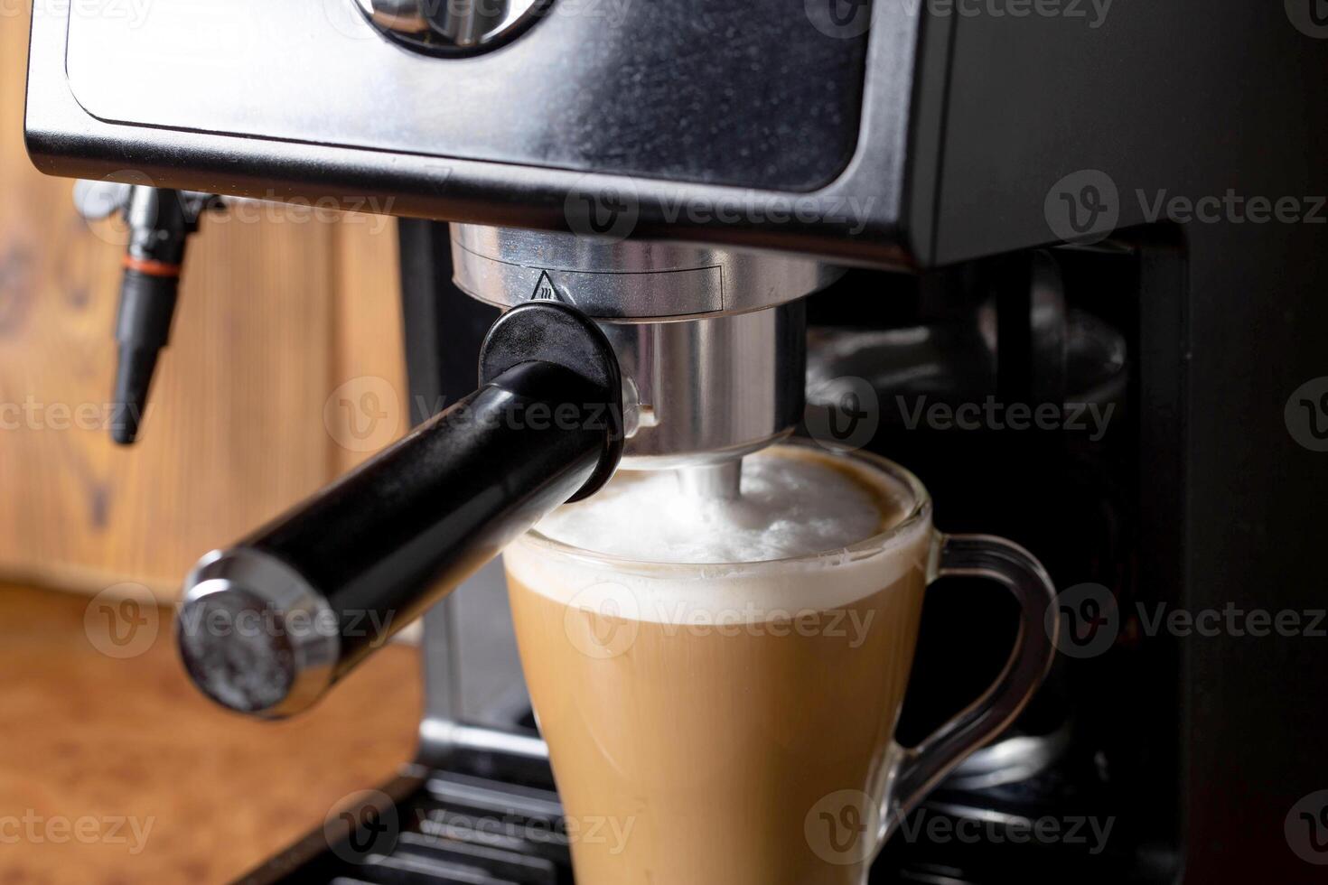 Making coffee with cappuccino milk in a cappuccino machine with a manual cappuccino maker on the background of a wooden table top. Close-up photo