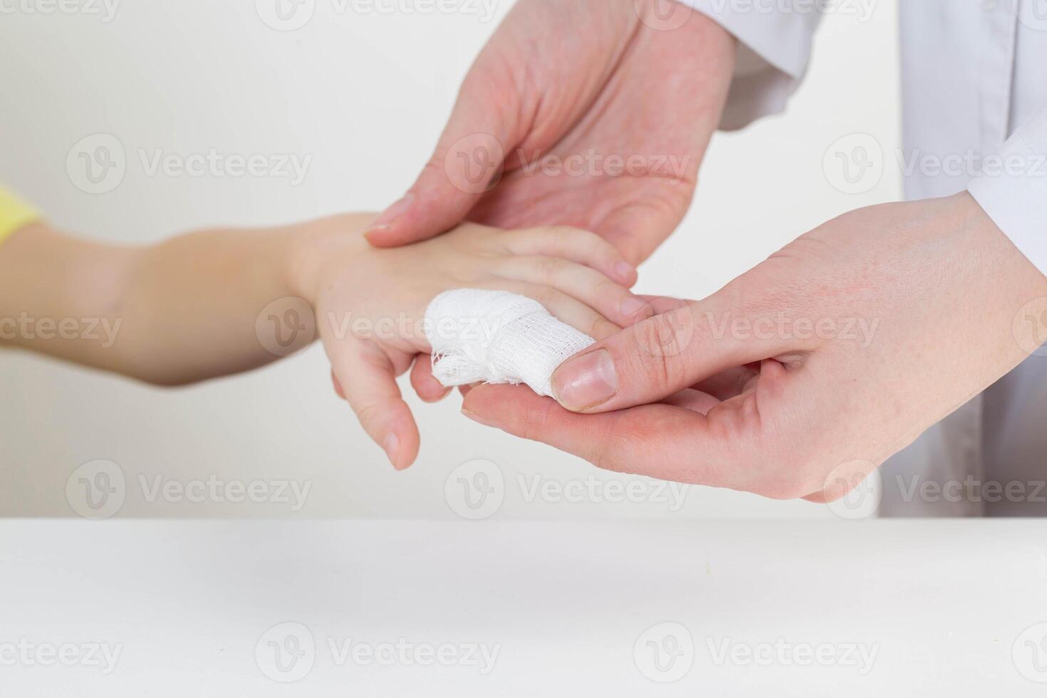 The hands of the doctor bandage the sore finger with a bandage of the child. Injury and wound on the finger in children, close-up photo