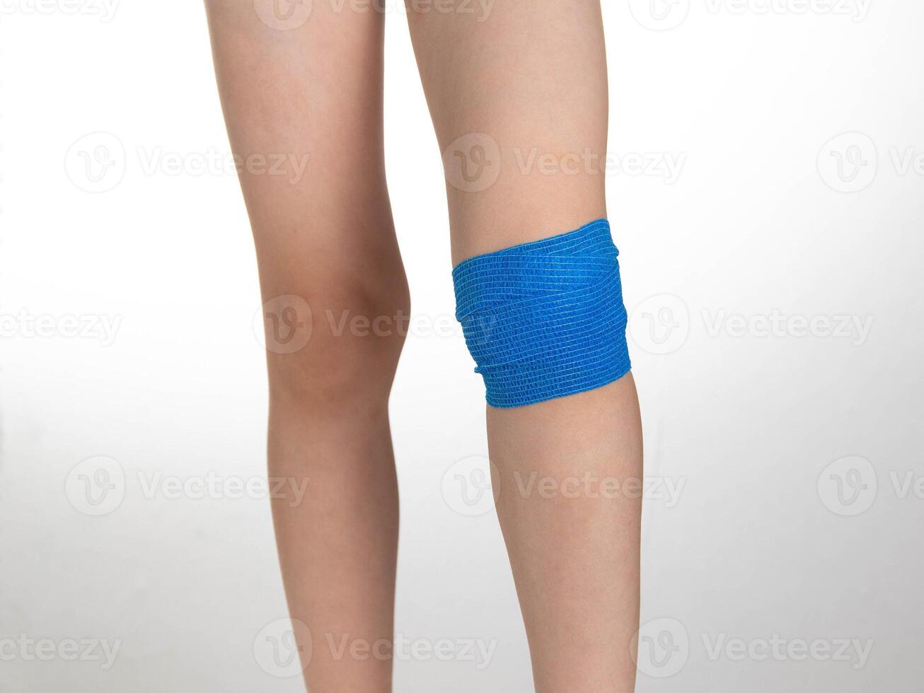 Blue elastic bandage on the knee joint on the child's leg. White background, treatment of knee pain and sprain, close-up photo