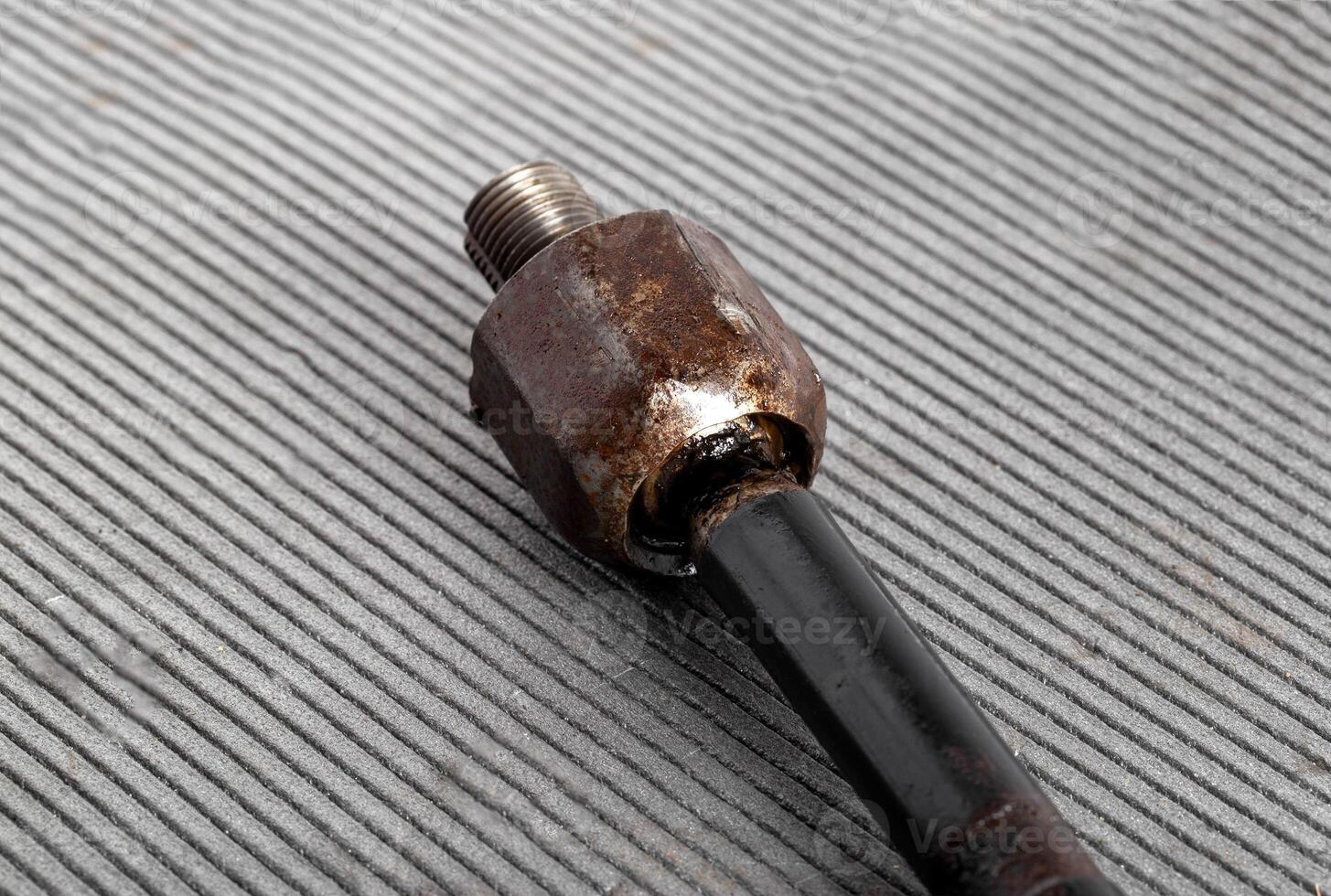 Old rusty steering rod on a gray background, close-up. photo