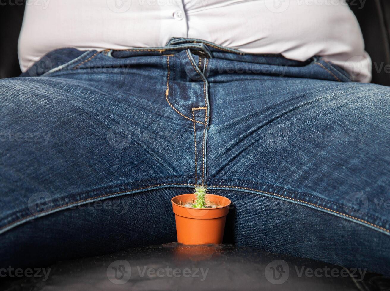 A man sits on a chair near the groin is a small cactus. The concept of male problems, a small penis, hormones and dysfunction in the genital area. Circumcision photo
