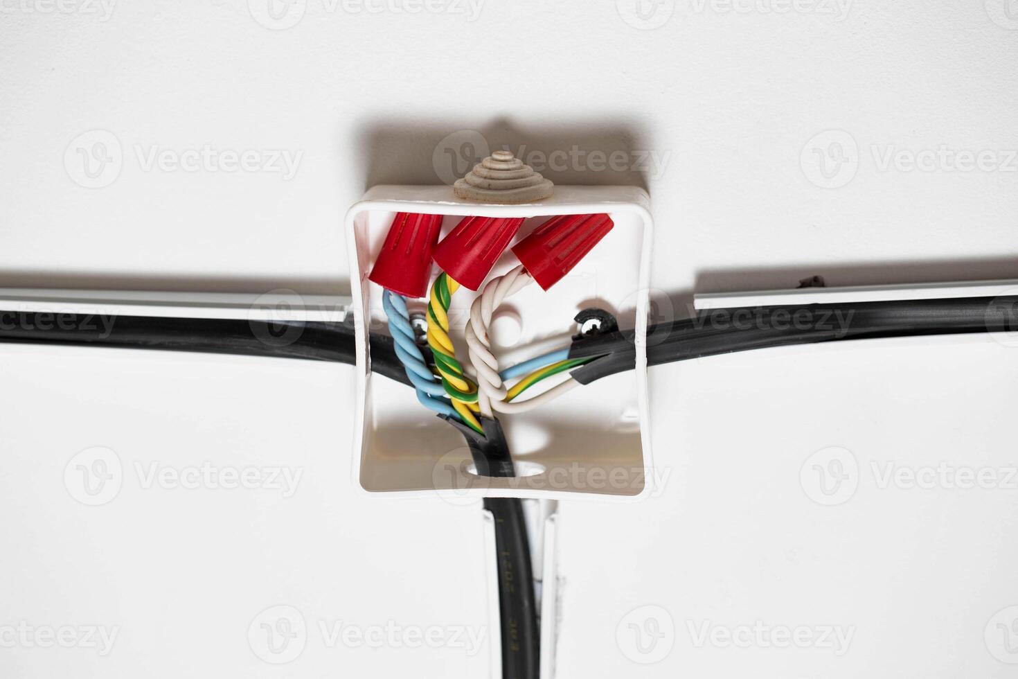 Connection of electrical wires in electrical boxes using red caps of connecting insulating clamps, close-up. Electrical installation photo