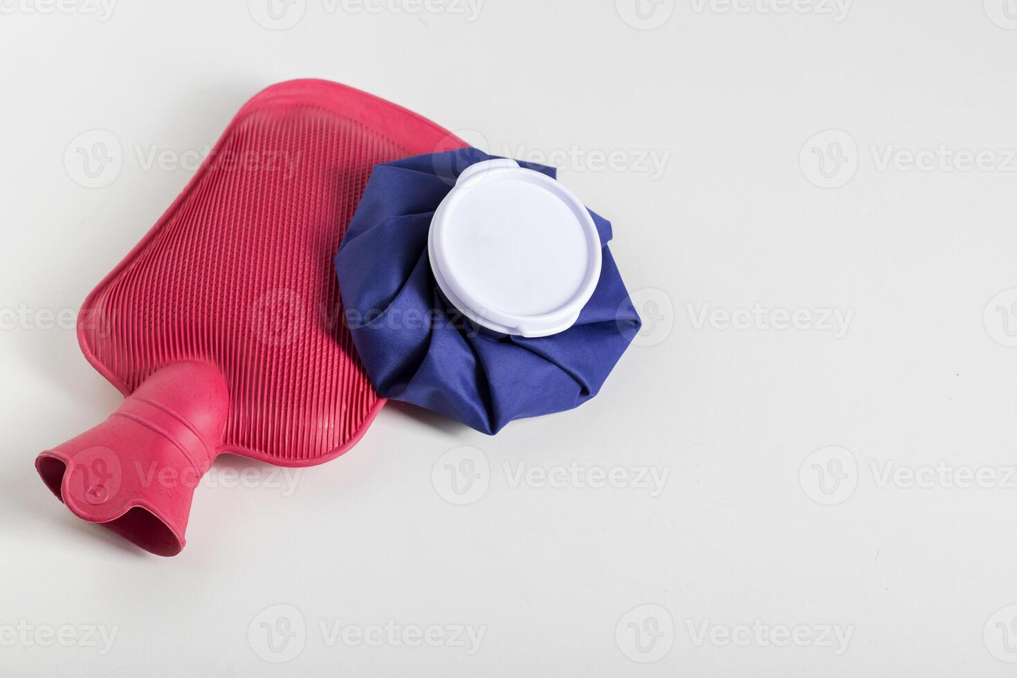 Red medical water heater and blue ice bag on a white background. The concept of treating diseases with heat and cold, heat therapy. Copy space for text photo