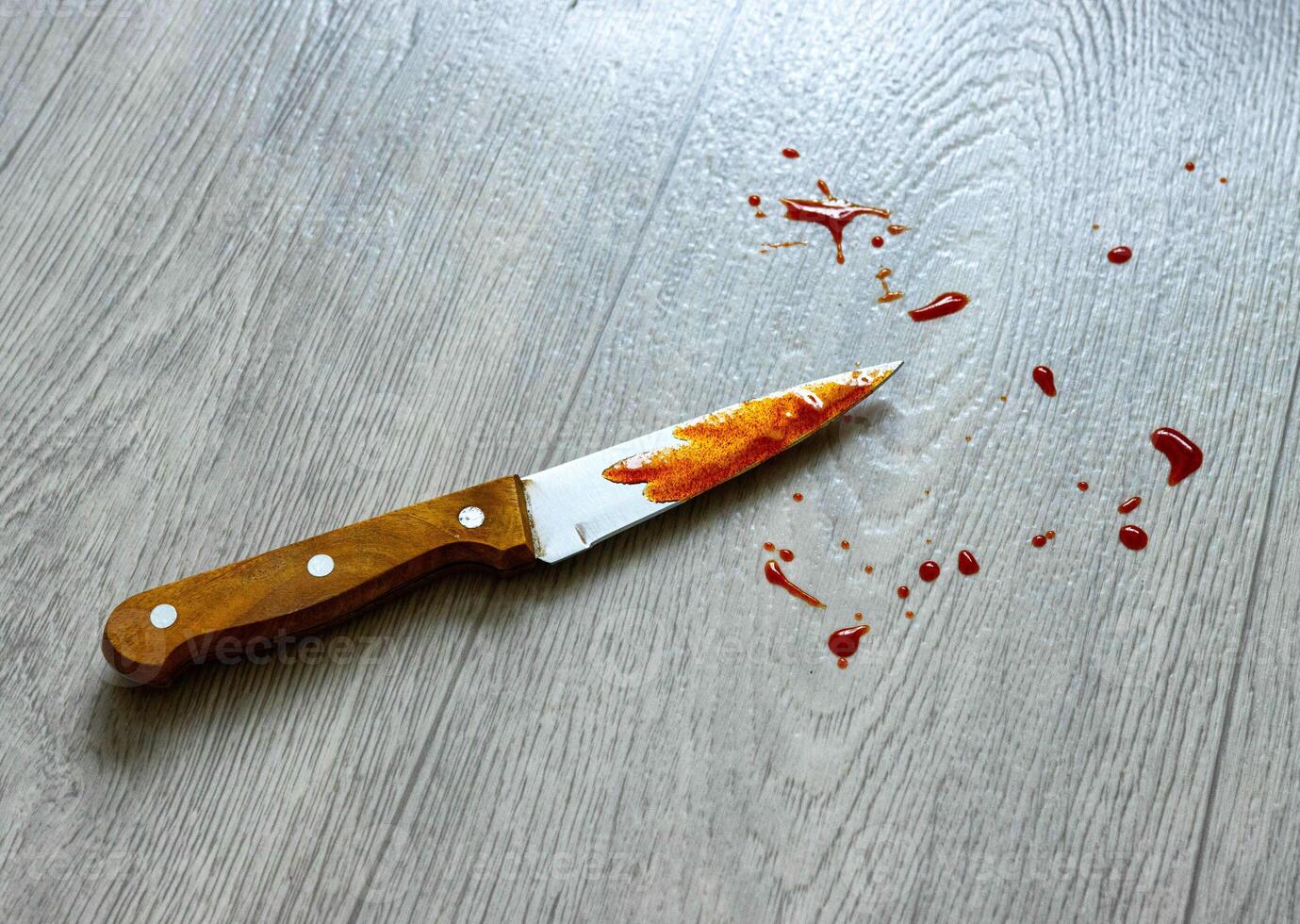 A knife with blood spatter lies on the linoleum, close-up. Concept of crime, robbery and theft photo