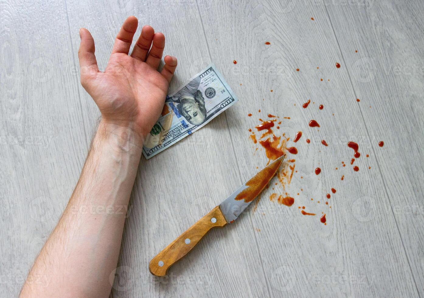 The hand of a murdered man with a bloody knife and money lies on the floor. Crime and murder, close-up photo