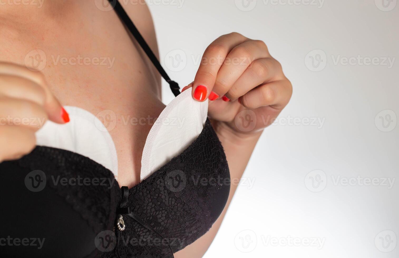 A girl in a black bra puts pads from the flow of milk in her bra. Soft, hypoallergenic breast pads. photo