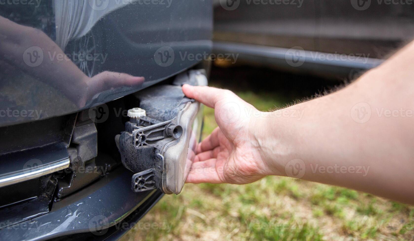Disassembling and removing the fog lamp from a car to replace a burnt out light bulb. Close-up photo