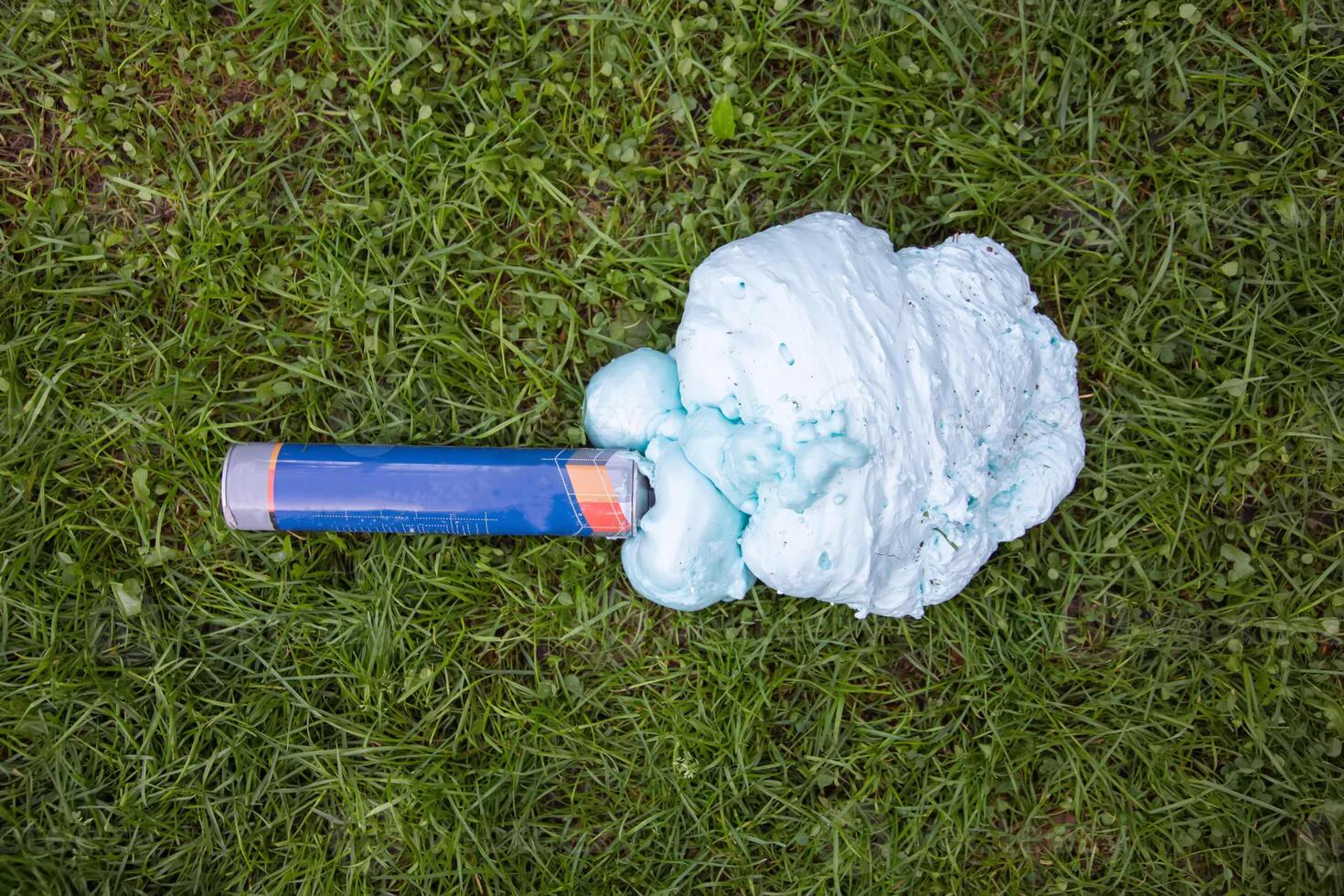 An exploded cylinder with construction foam on the grass. Balloon defect, close-up photo