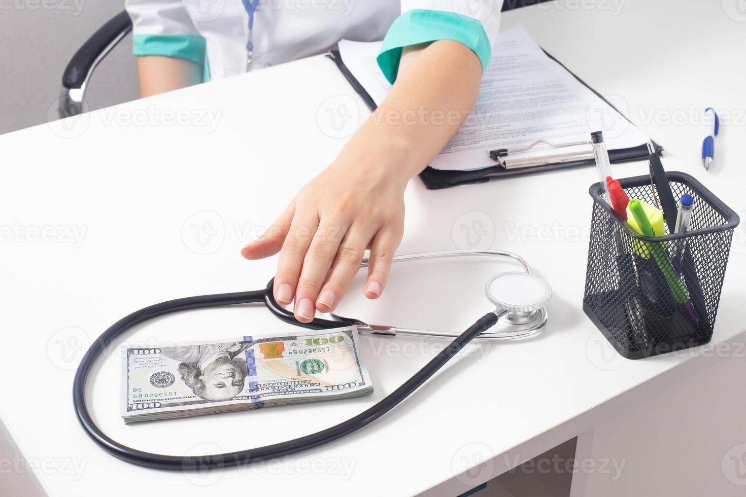 The doctor reaches out on the table for money in dollars. The concept of bribery in healthcare photo