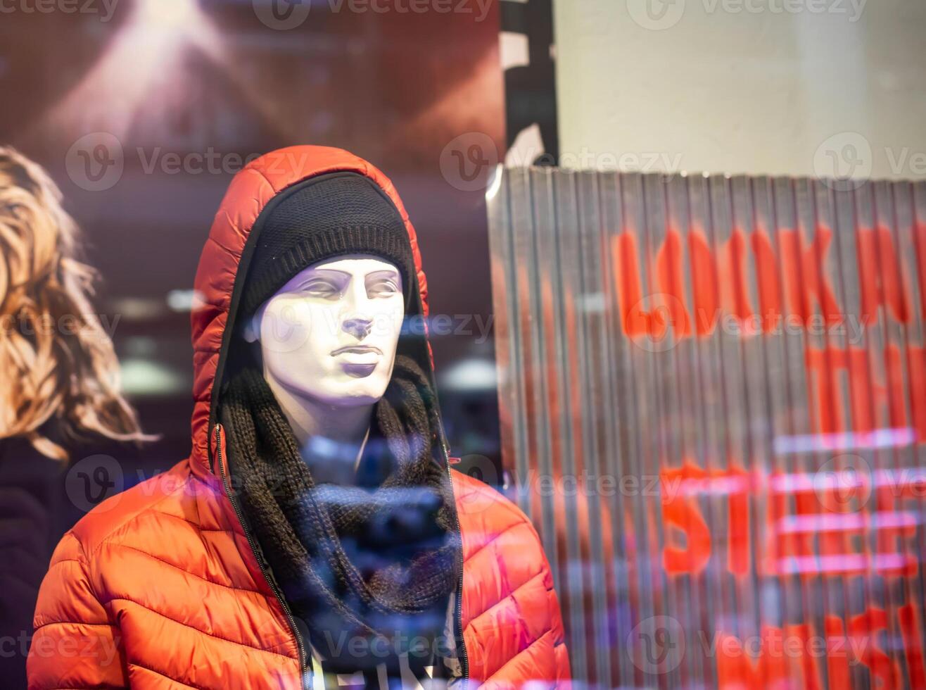 male mannequin in a modern store in a jacket with a hood and a scarf. The concept of selling fashionable autumn and winter clothes, background photo