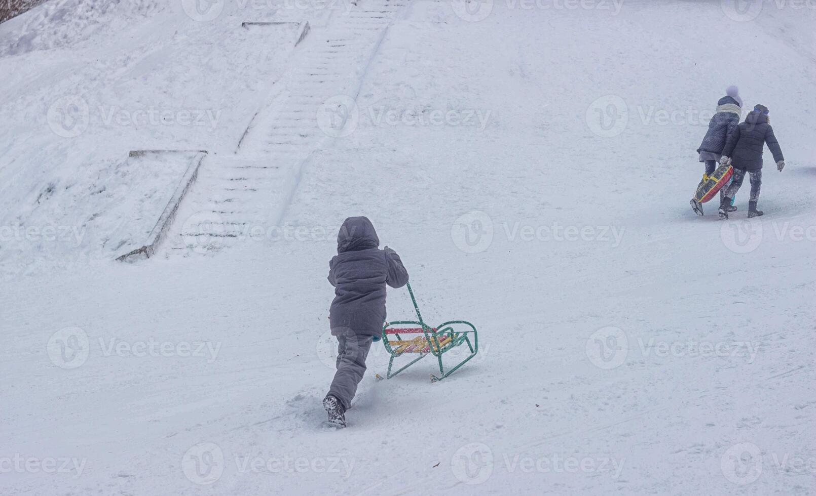 children ride a sled on a snow mountain, sledding from a hill in winter, background photo