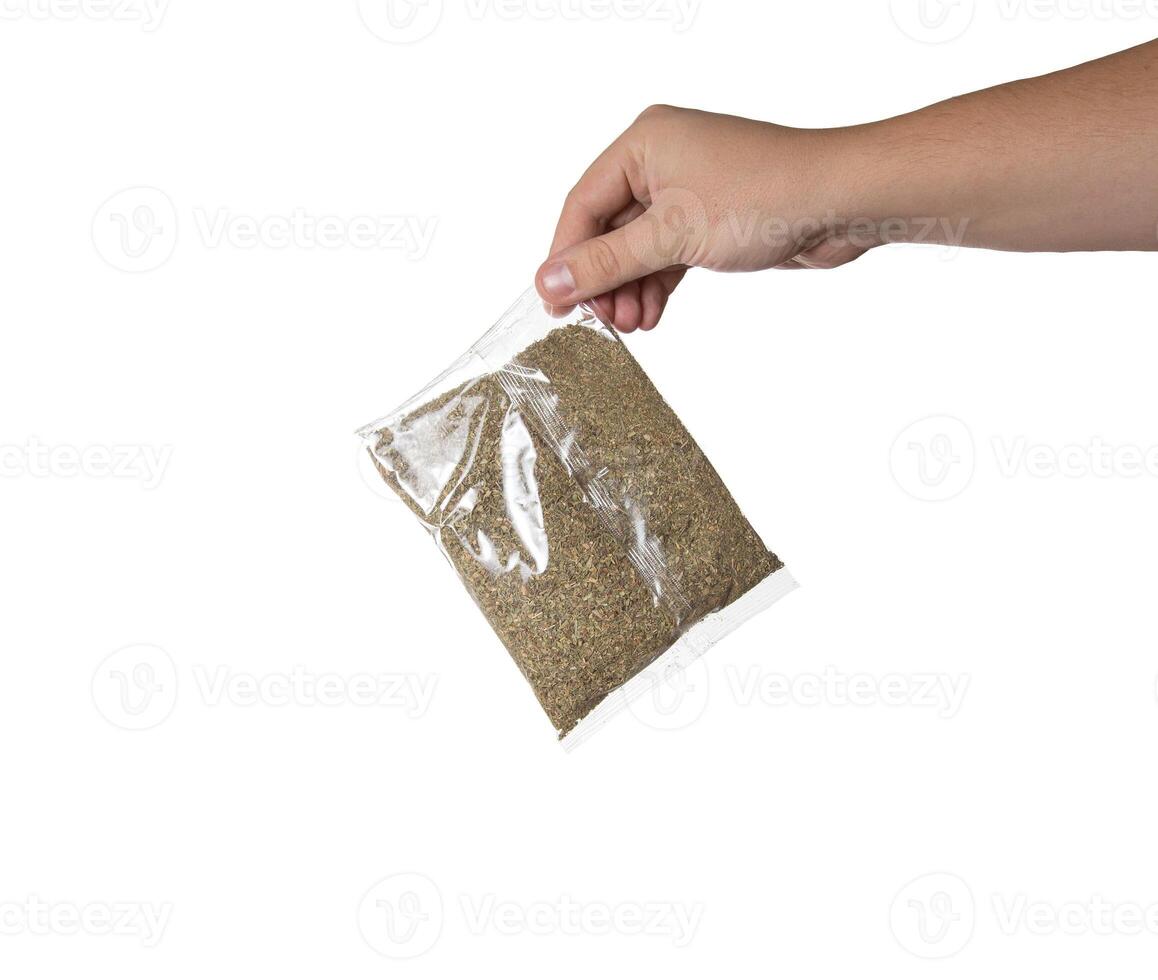 A mixture of dry spices in a transparent bag in a man's hand on a white background, close-up. Isolate photo