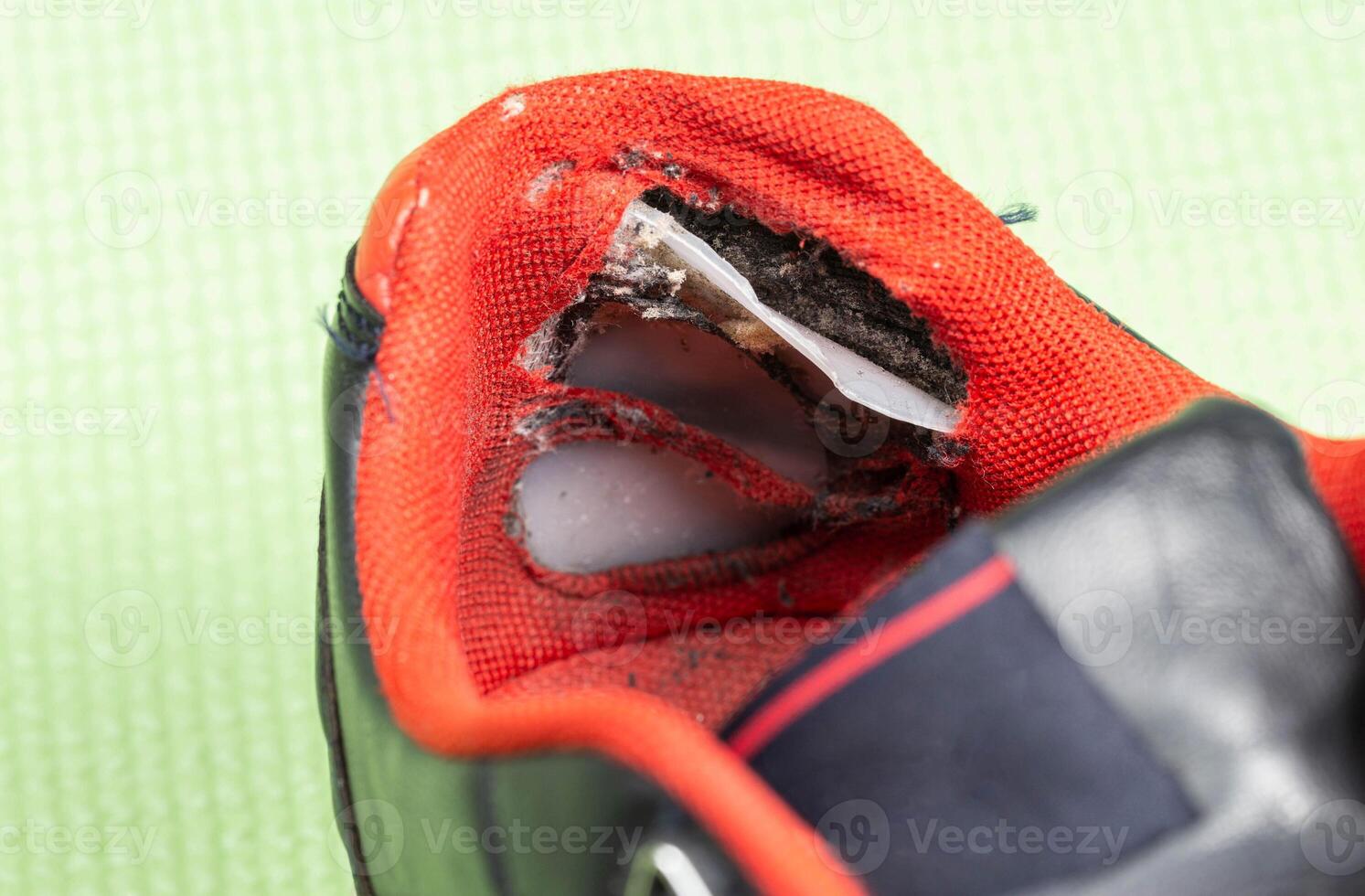 A ripped backdrop in sporty multicolored sneakers. Poor quality shoes, close-up photo