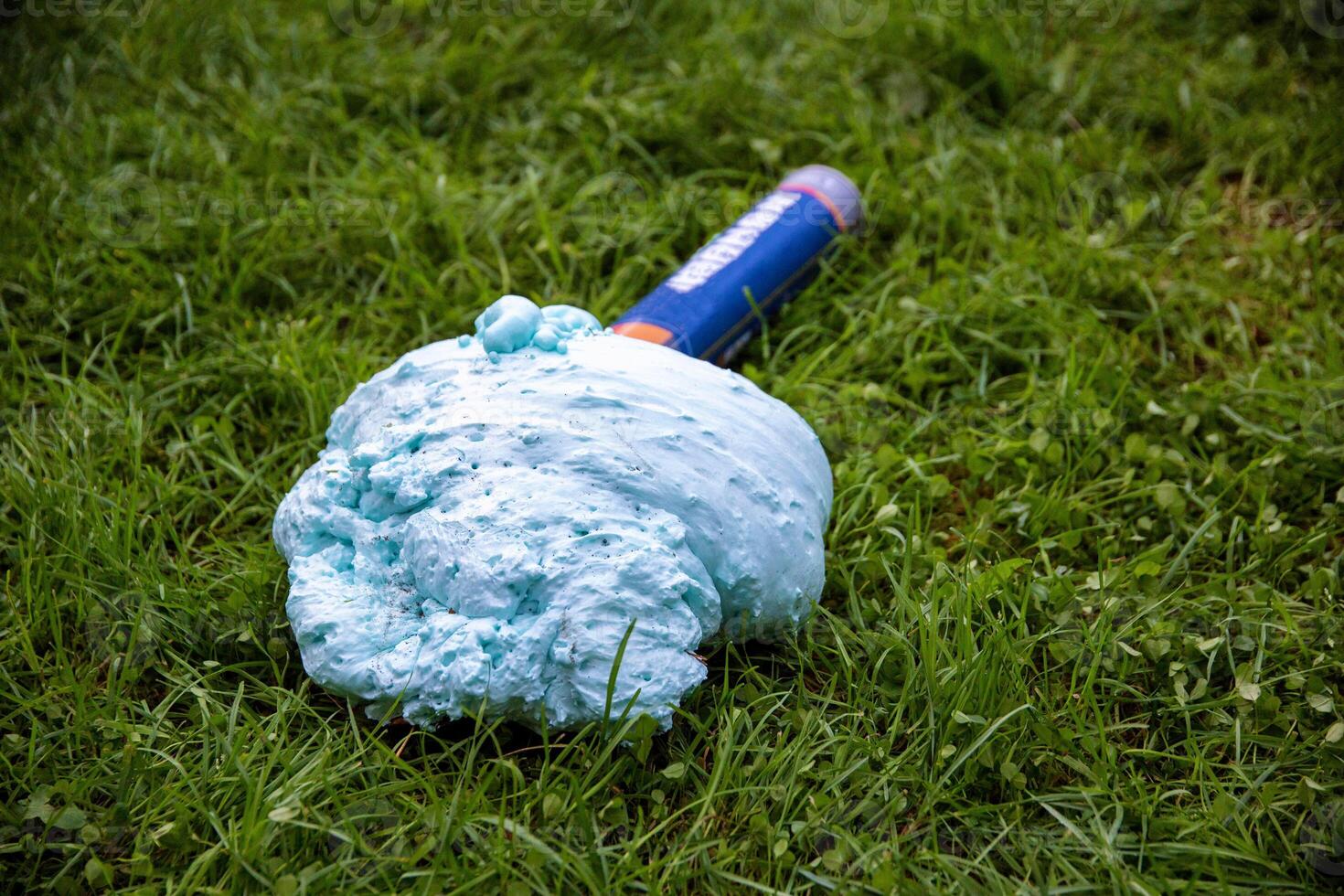 An exploded cylinder with construction foam on the grass. Balloon defect, close-up photo