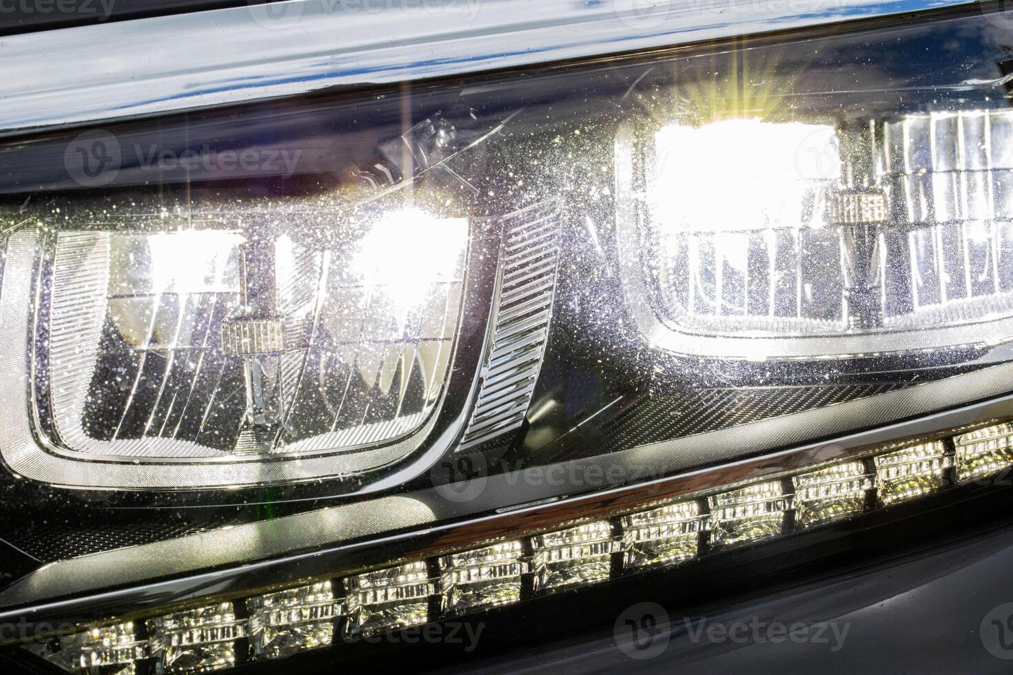 Dots from stones on the headlight of a car, sandblasting and shagreen from sand particles. Headlamp glass care, detailing photo
